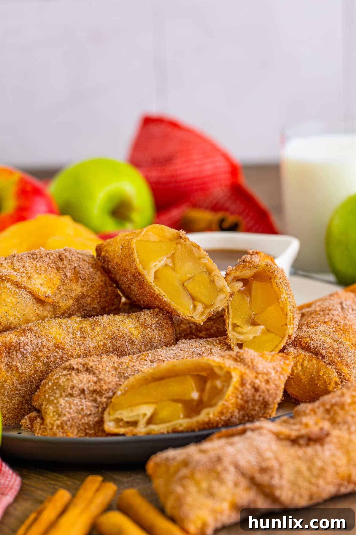 Crispy apple pie egg rolls, perfectly golden and dusted with cinnamon sugar, arranged on a rustic plate, ready to be enjoyed as a delightful dessert.