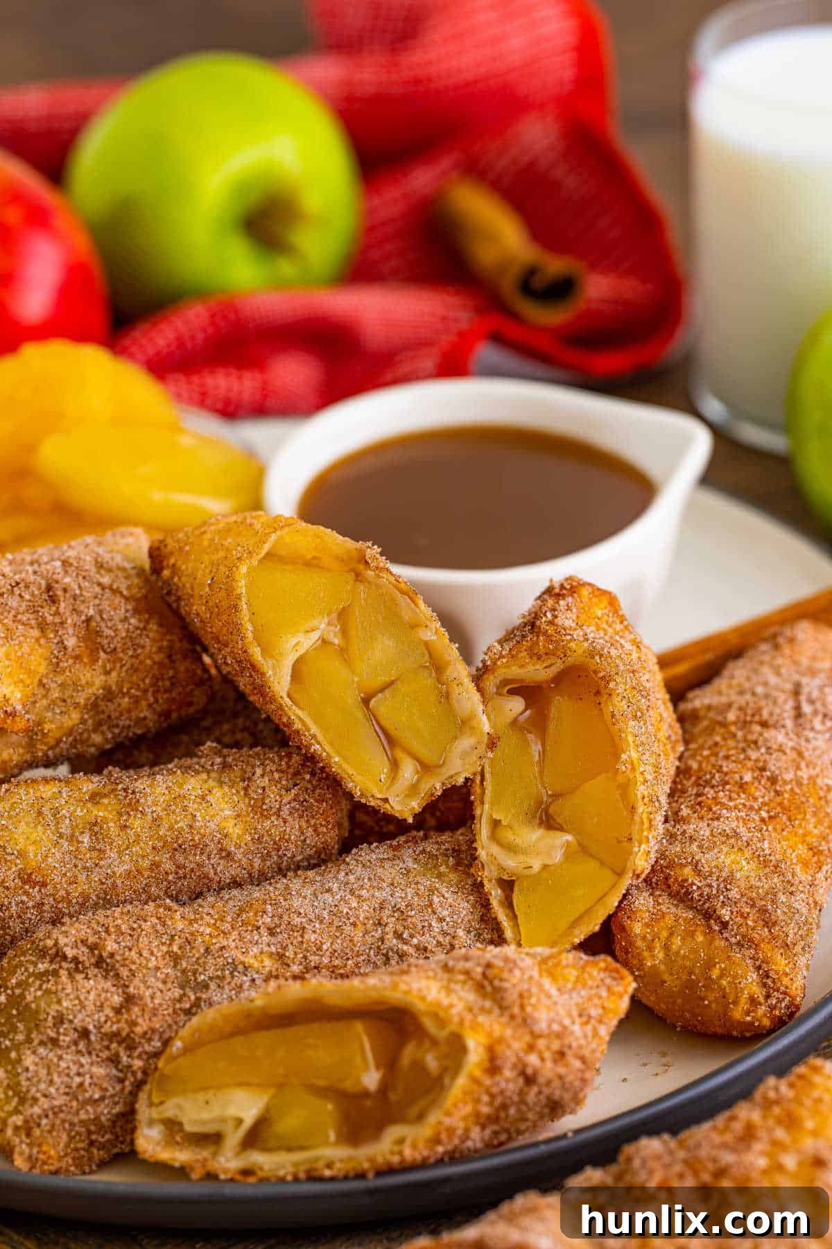 A plate of golden-brown apple pie egg rolls dusted with cinnamon sugar, showcasing their crispy texture and inviting presentation.