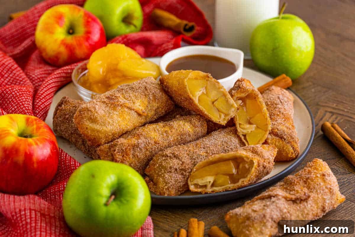 A beautifully presented plate of apple pie egg rolls, with a small dish of golden caramel dipping sauce, ready for sharing.