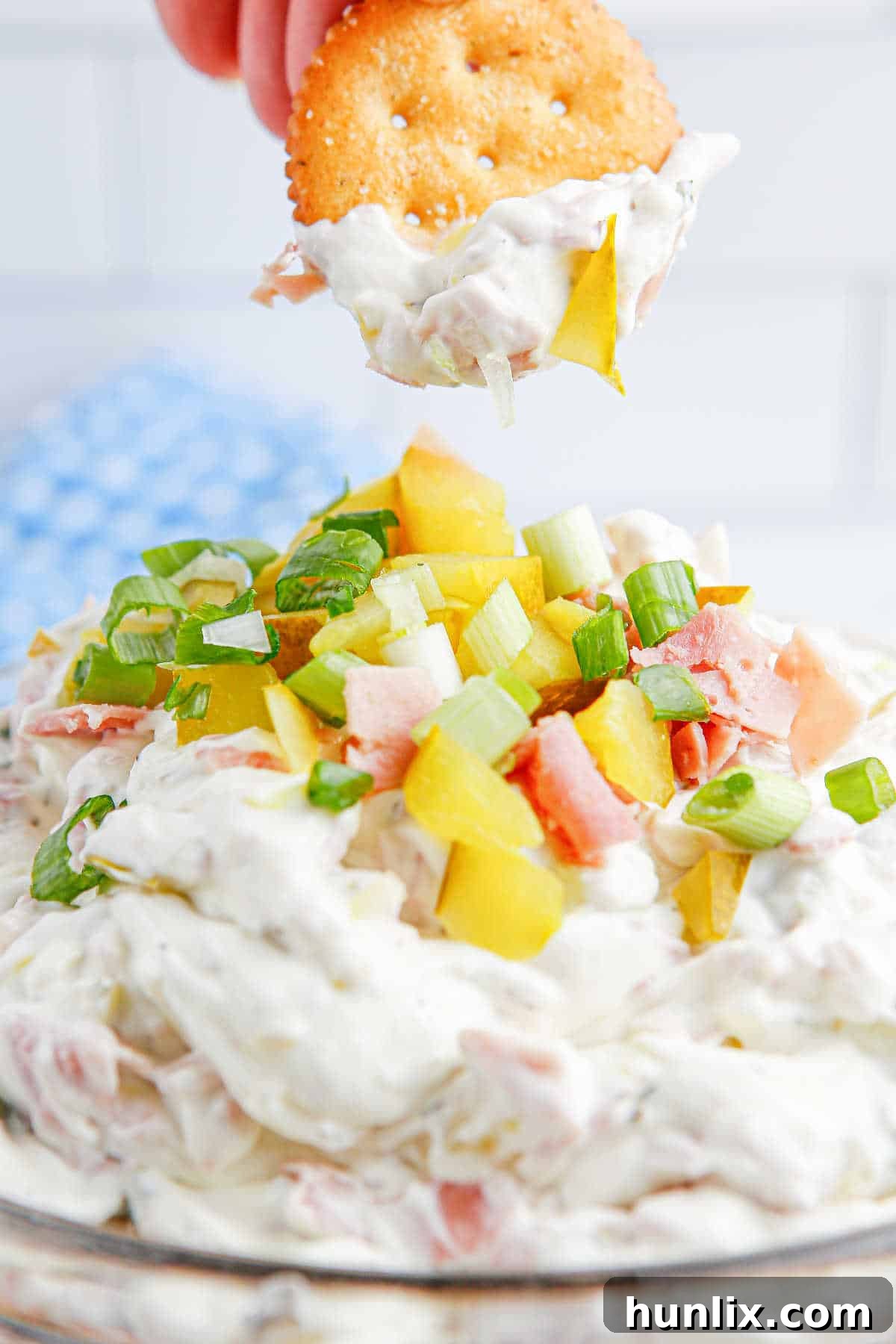 A crisp cracker expertly topped with a generous dollop of creamy dill pickle dip, showcasing its enticing texture and the visible pieces of dill and pickle.