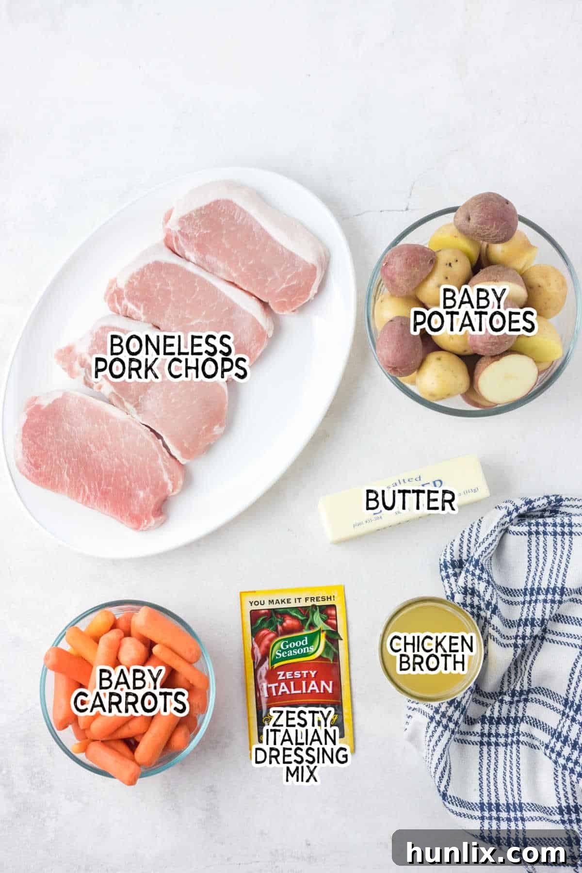 Fresh ingredients laid out for making Crockpot Italian Pork Chops and Veggies: potatoes, carrots, pork chops, broth, dressing mix, and butter.
