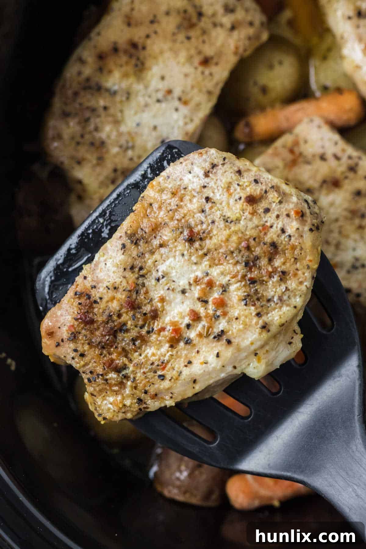 A tender Italian pork chop being lifted from a slow cooker with a spatula, ready to serve.