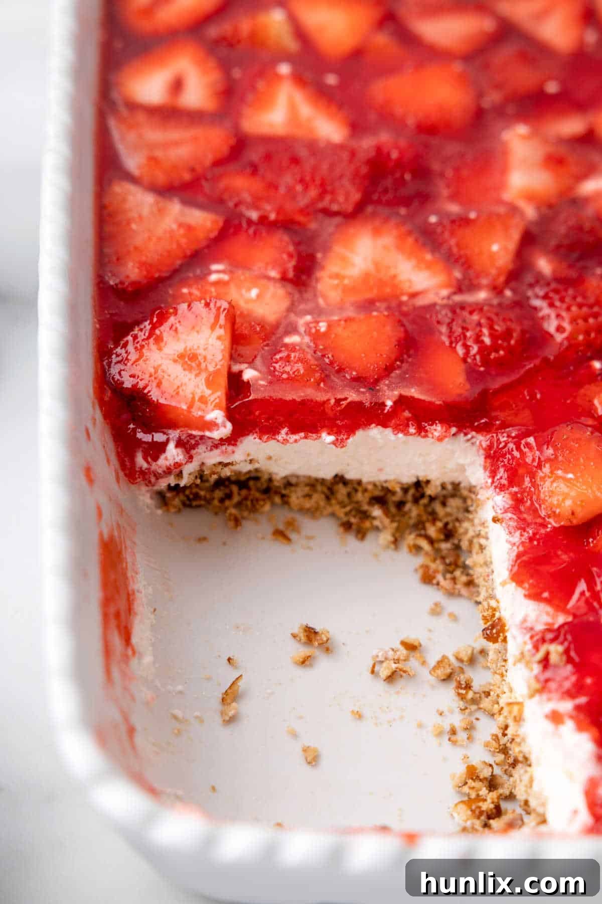 Strawberry pretzel salad in a pan with a piece cut out.