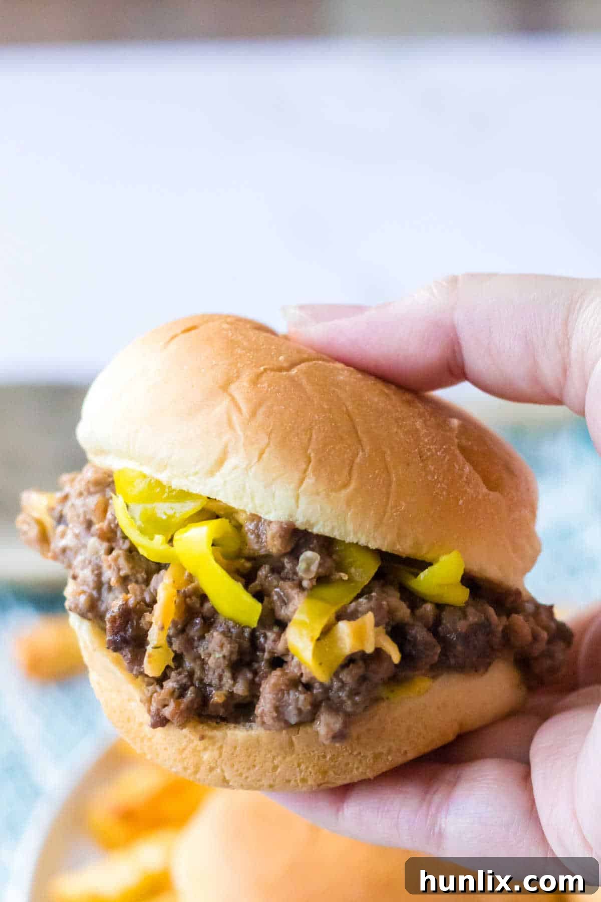 Hearty Slow Cooker Mississippi Sloppy Joes 8 A hand holding a perfectly assembled Mississippi Sloppy Joe sandwich, showing the generous filling.
