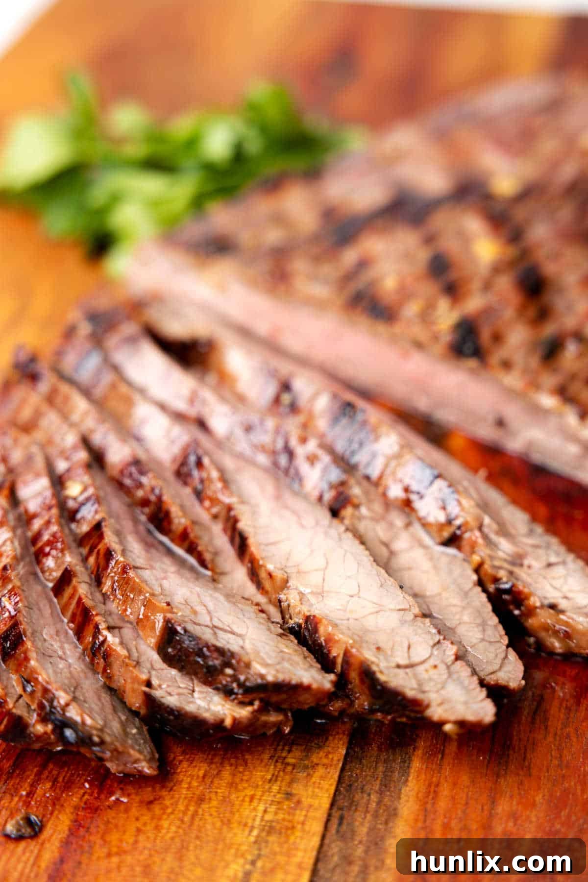 Slices of grilled flank steak on a wooden cutting board.