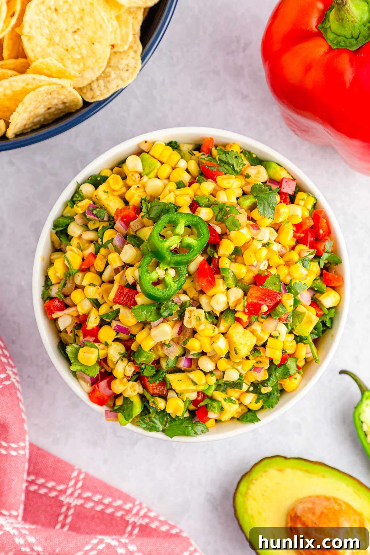 Zesty Corn Salsa 2 A large bowl of vibrant corn salsa, featuring yellow corn, red bell peppers, green cilantro, and red onions, ready to be served.