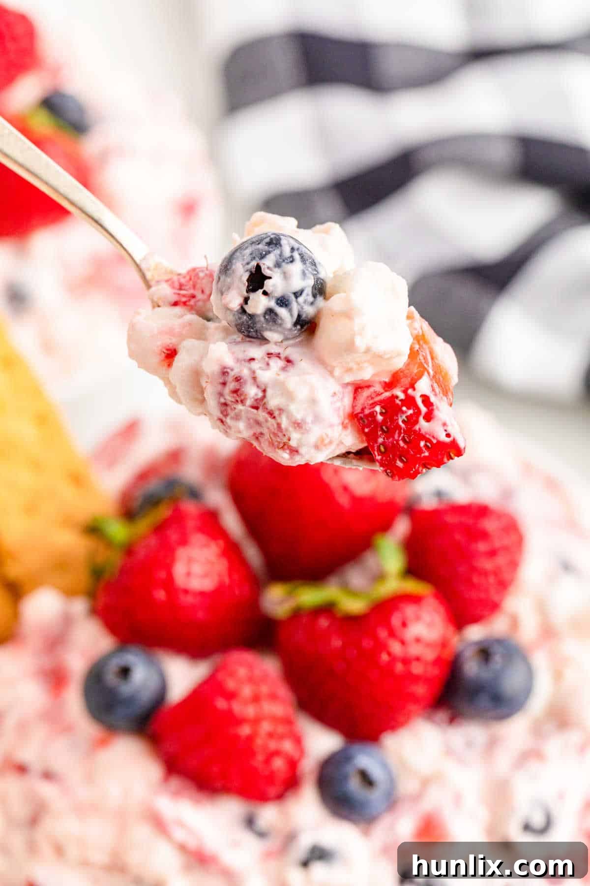 A spoonful of Berry Cheesecake Fluff, showcasing its light, creamy texture and the mix of fresh berries.