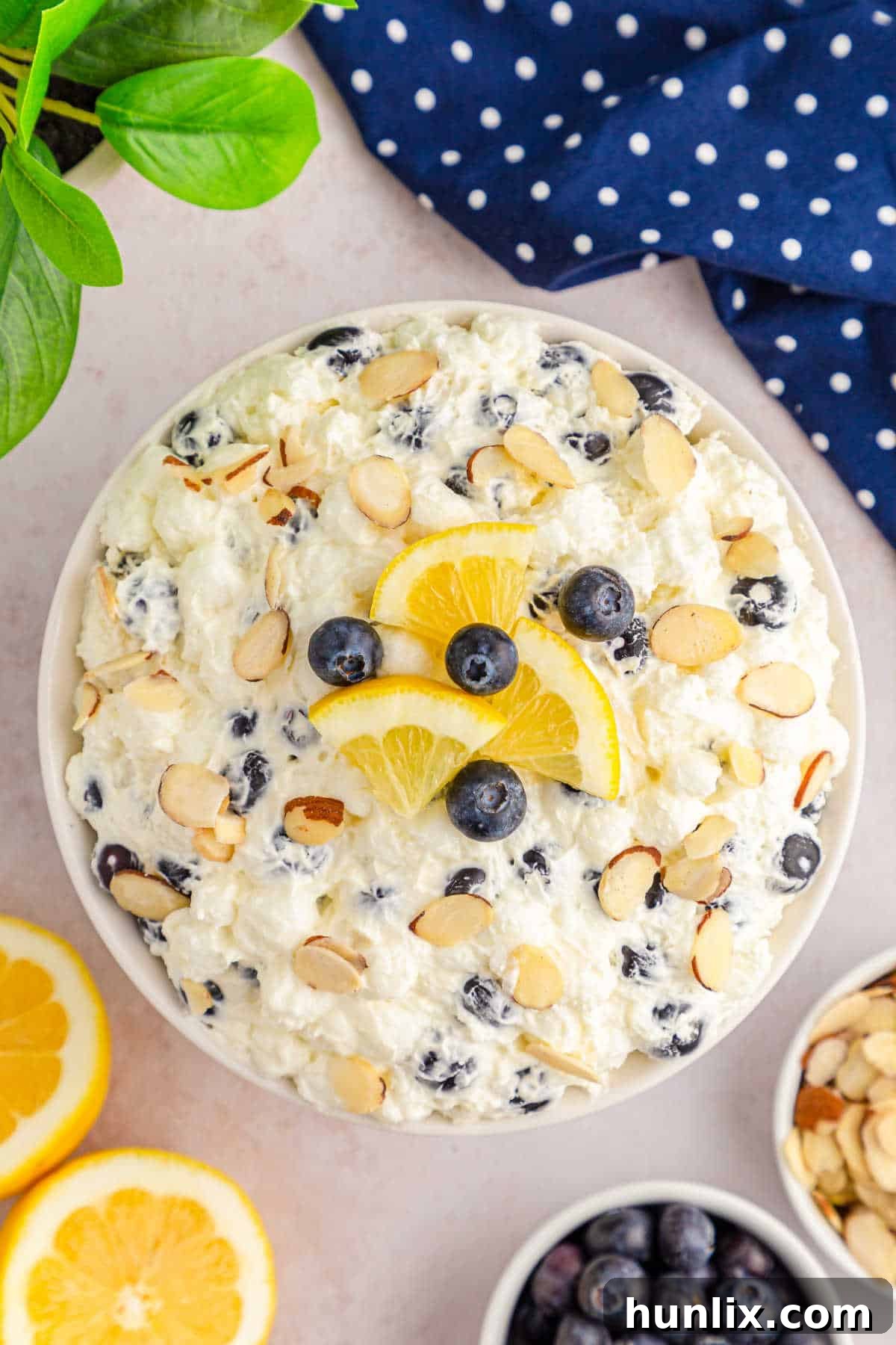 A spoonful of creamy Lemon Blueberry Fluff scooped from a large bowl, highlighting its delightful texture and fresh ingredients.