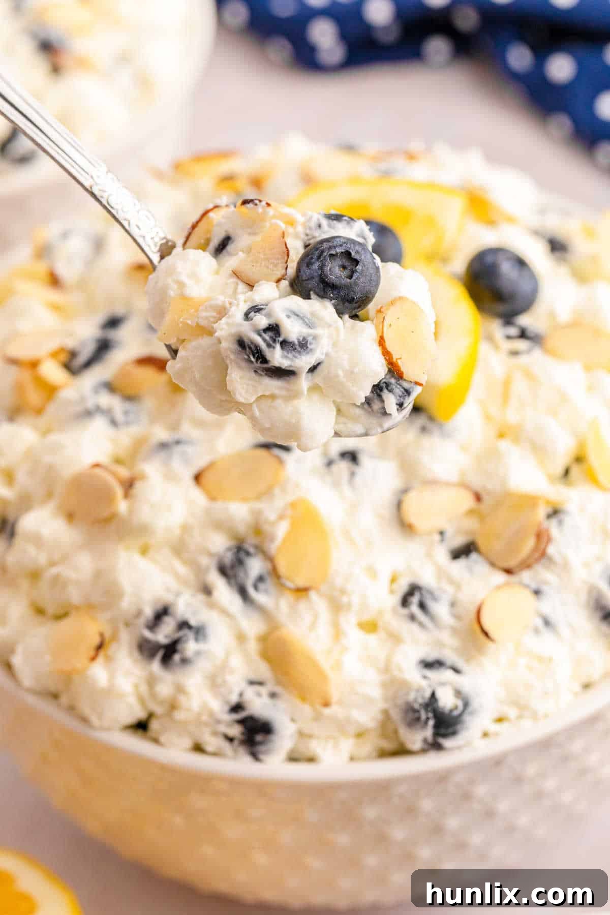 A close-up of a spoonful of Lemon Blueberry Fluff, showcasing the creamy texture with visible blueberries and marshmallows, ready to be enjoyed.