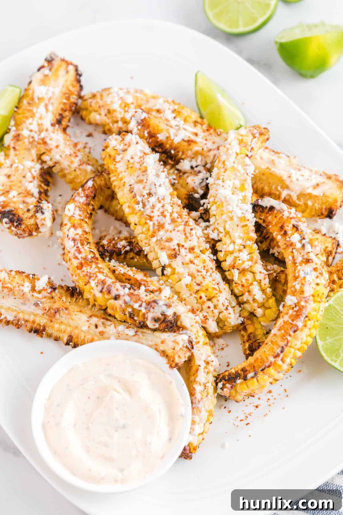 Air fryer corn ribs presented on a plate with a side of dipping sauce, garnished with fresh cilantro.