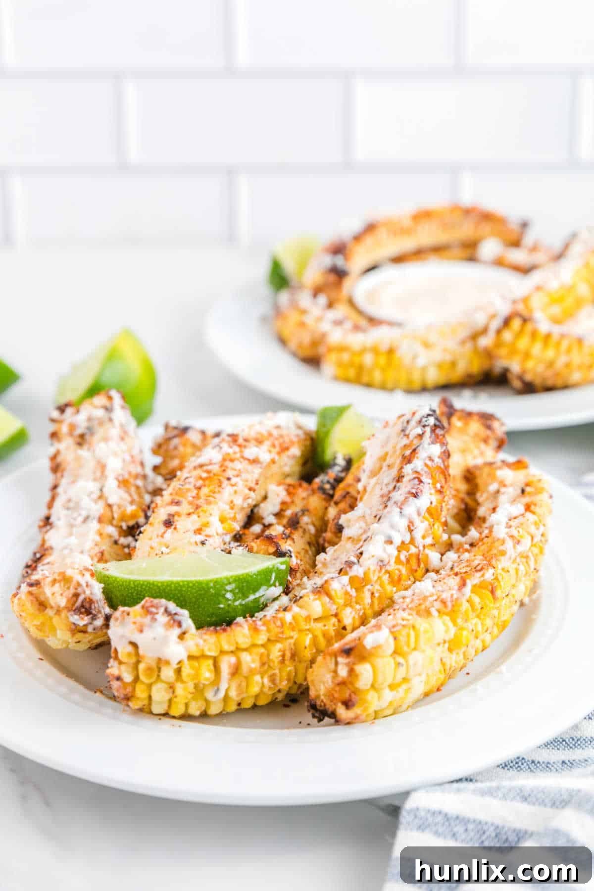Air fryer corn ribs on a plate, garnished with lime wedges and fresh cilantro.