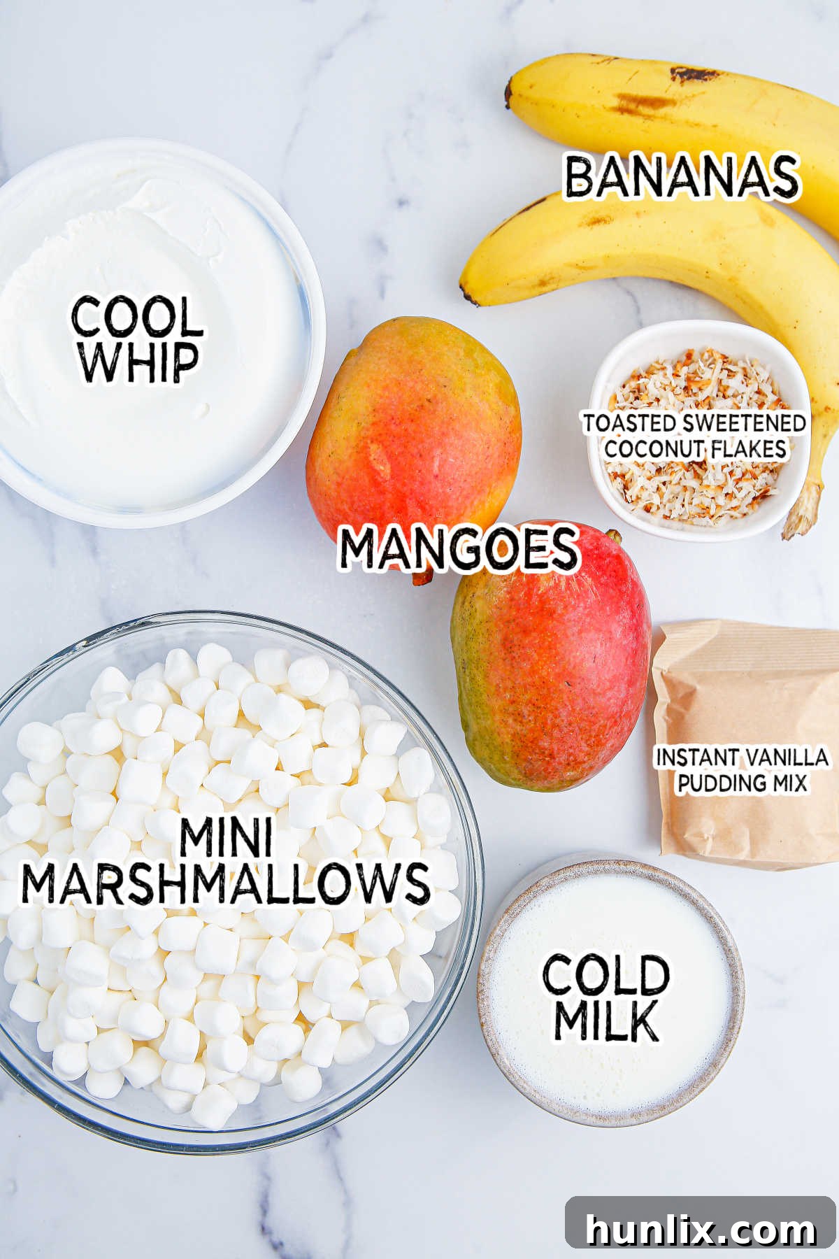 Tropical Mango Banana Fluff 3 A selection of fresh ingredients including mangoes, bananas, mini marshmallows, Cool Whip, milk, and vanilla pudding mix, laid out on a kitchen counter, ready to be used for the mango banana marshmallow salad.