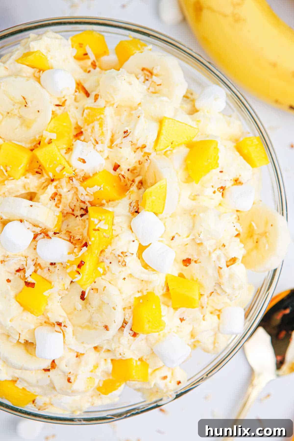 Tropical Mango Banana Fluff 7 A beautifully presented bowl of mango banana marshmallow salad, garnished with toasted coconut flakes, ready to be enjoyed.