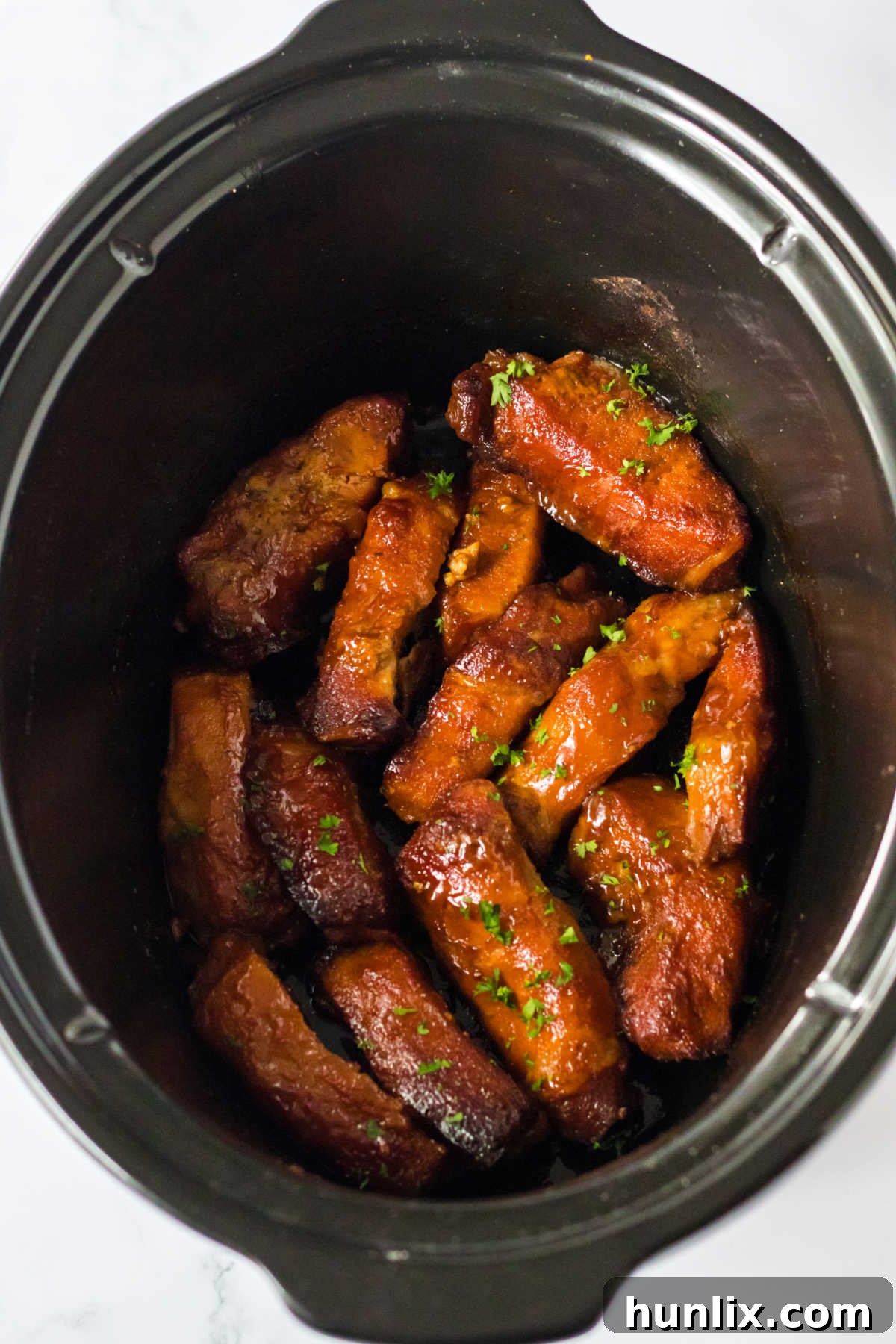 Melt-in-Your-Mouth Slow Cooker Country Ribs 2 Country style ribs in a crockpot, coated in a sweet peach BBQ sauce.