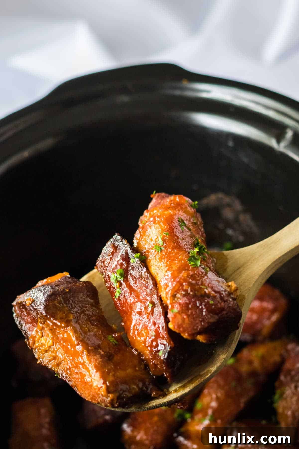 Melt-in-Your-Mouth Slow Cooker Country Ribs 5 Close-up of a serving spoon holding a tender country-style rib.