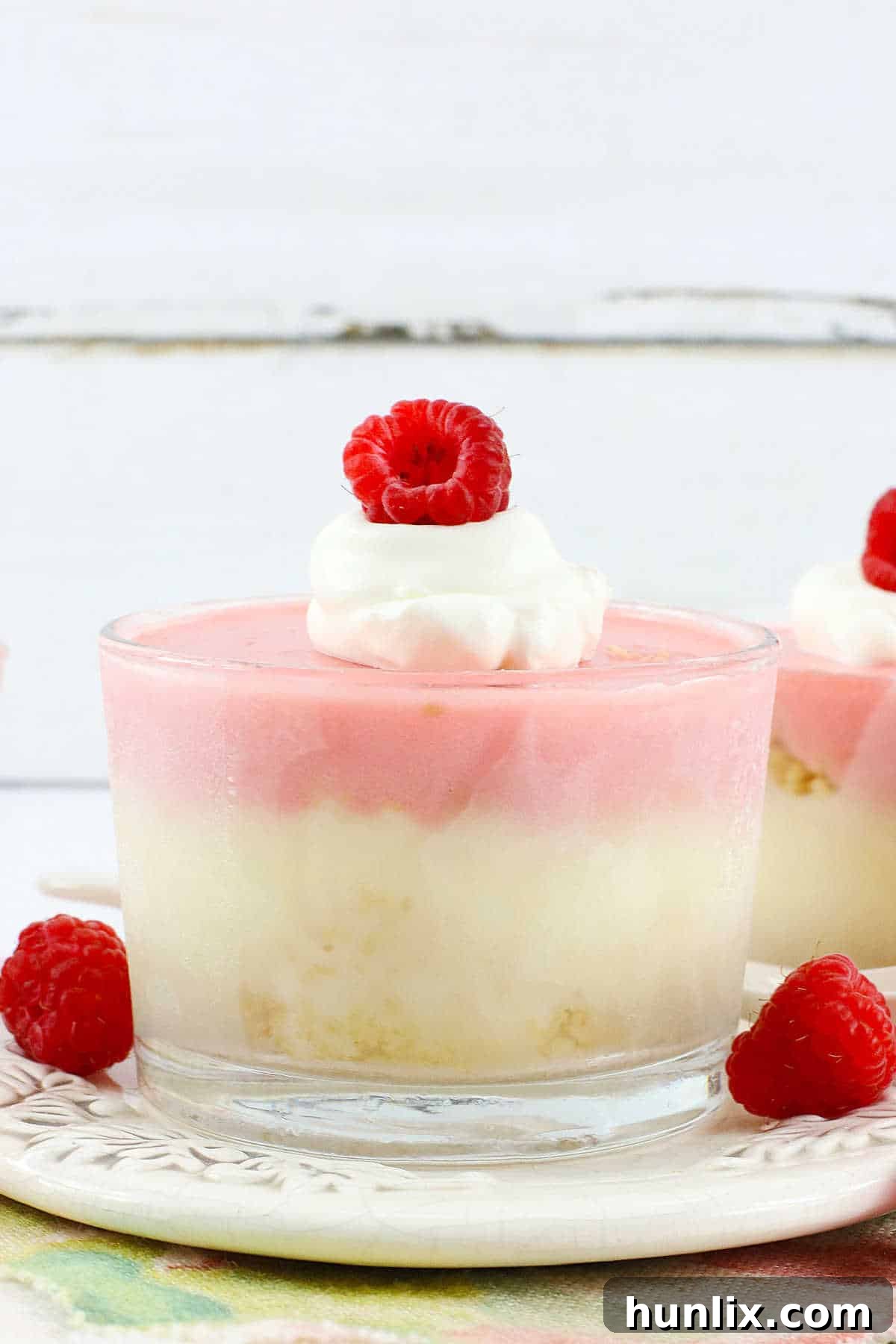 Raspberry cheesecake cups artfully arranged in individual containers.