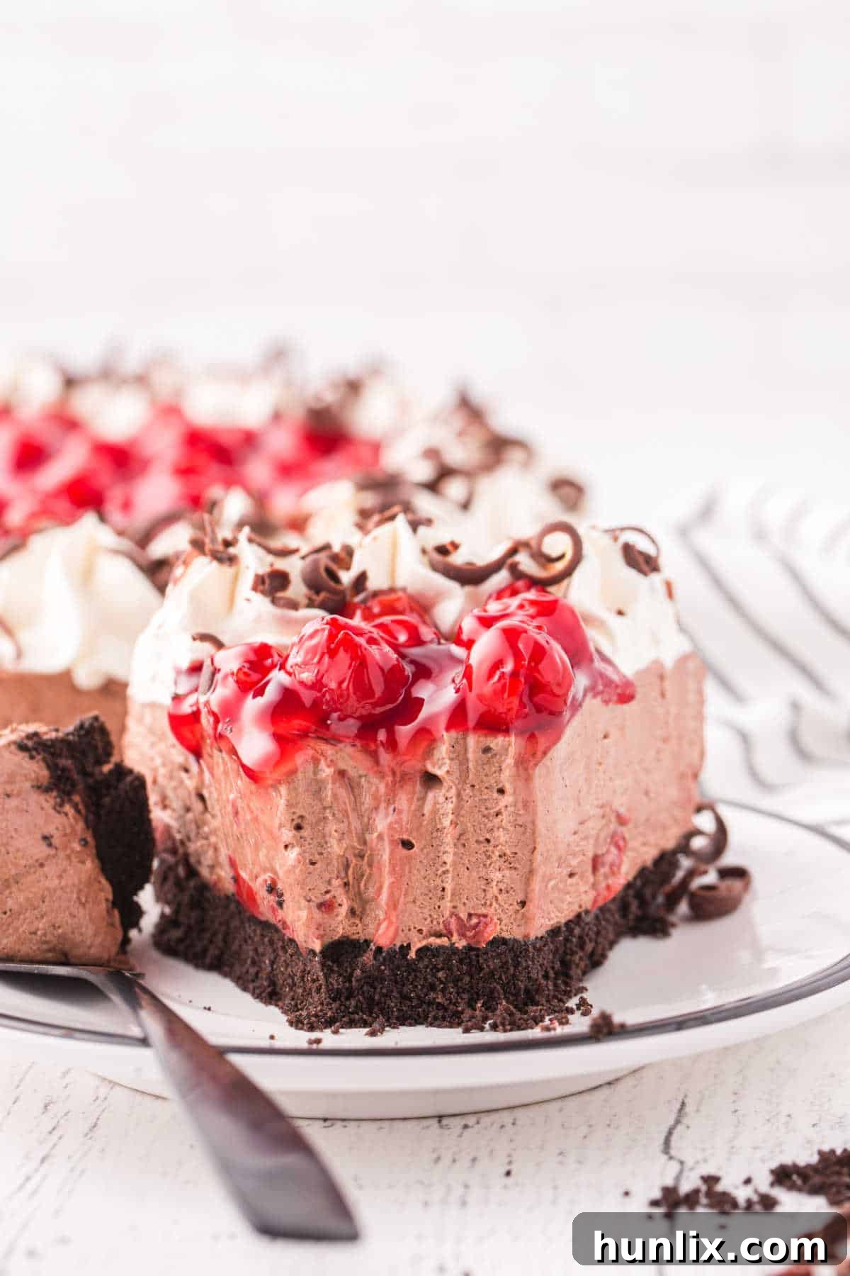 A slice of black forest cheesecake on a plate with a bite taken, showing the rich texture.