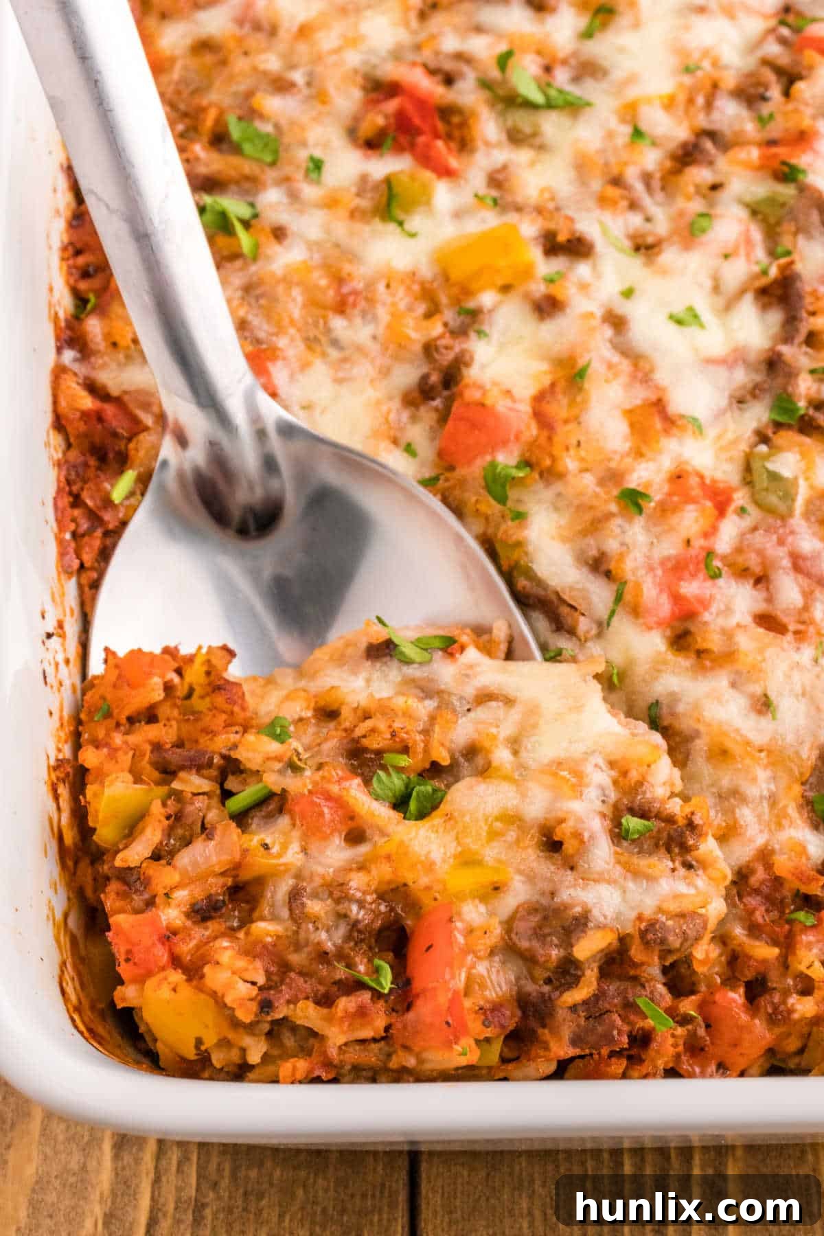 A large serving spoon scooping stuffed pepper casserole.