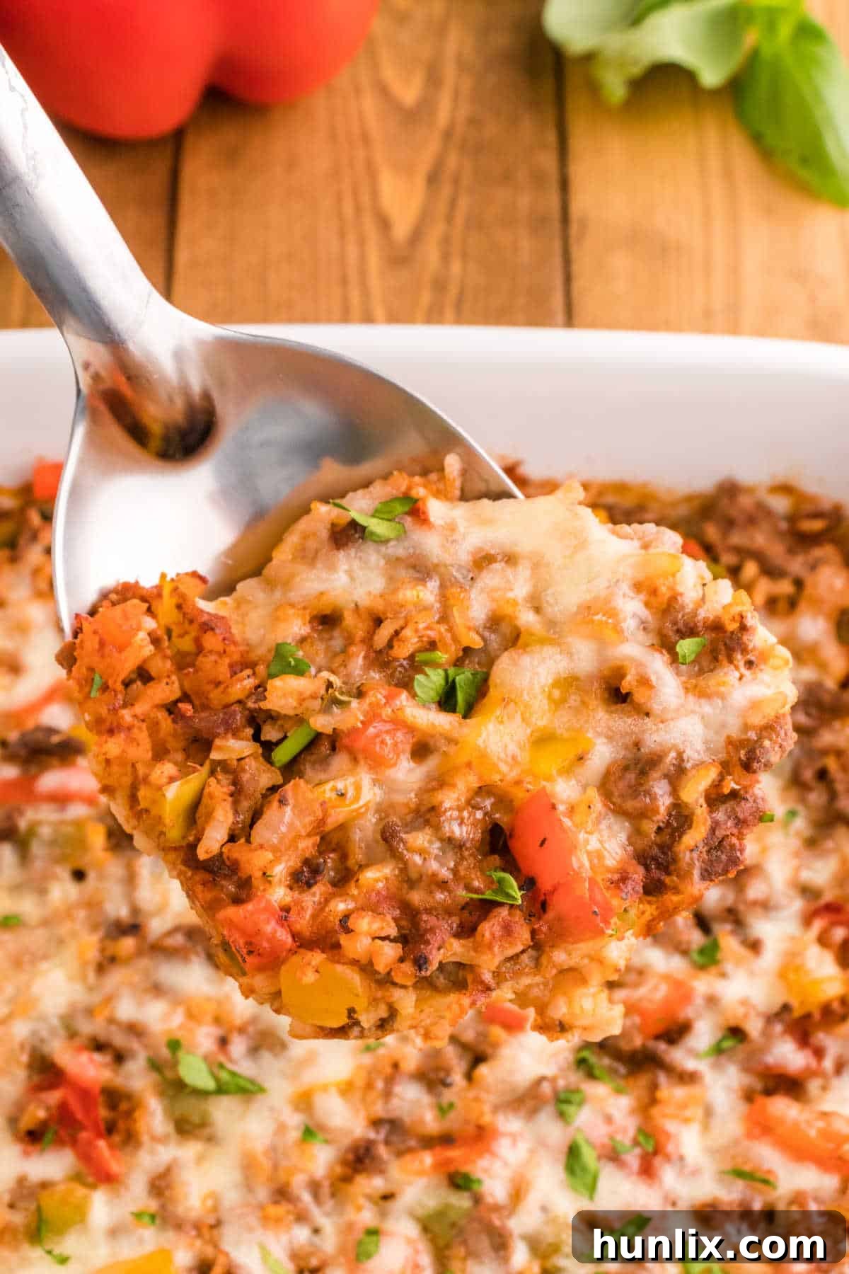 A spoon lifting a portion of stuffed pepper casserole from the dish.