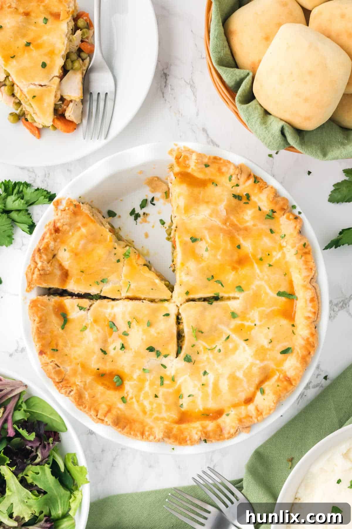 A beautifully baked chicken pot pie with a few slices already cut, revealing the creamy chicken and vegetable filling.