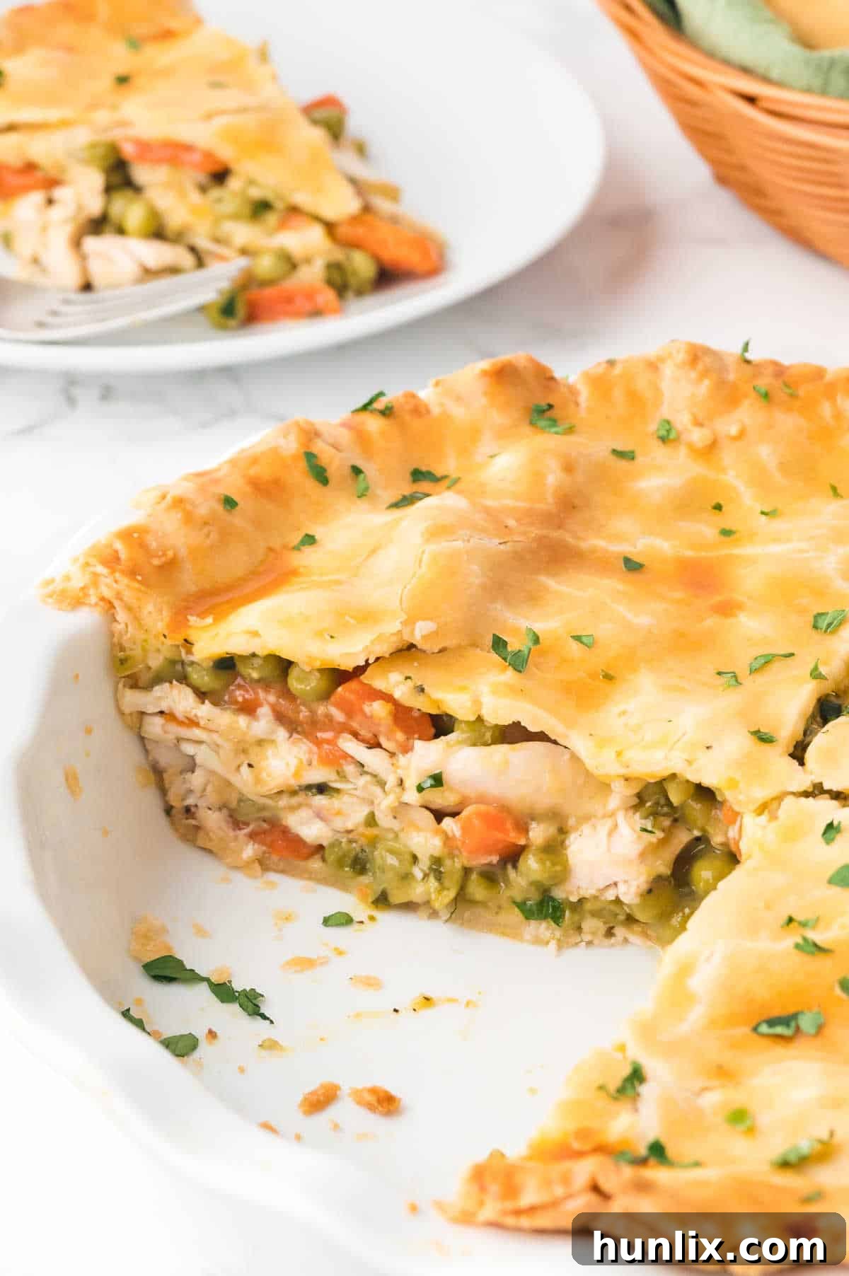 A baked chicken pot pie with several pieces already removed, showcasing the generous filling and crispy crust.