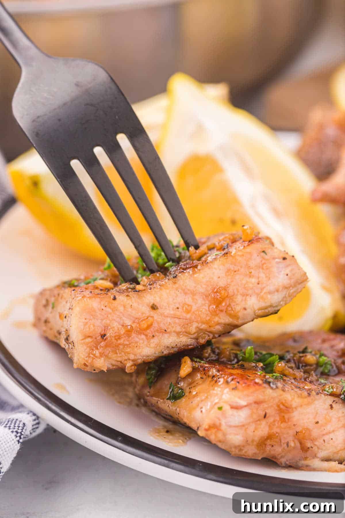 A single honey garlic pork chop on a fork, showing its juicy interior and sticky glaze.