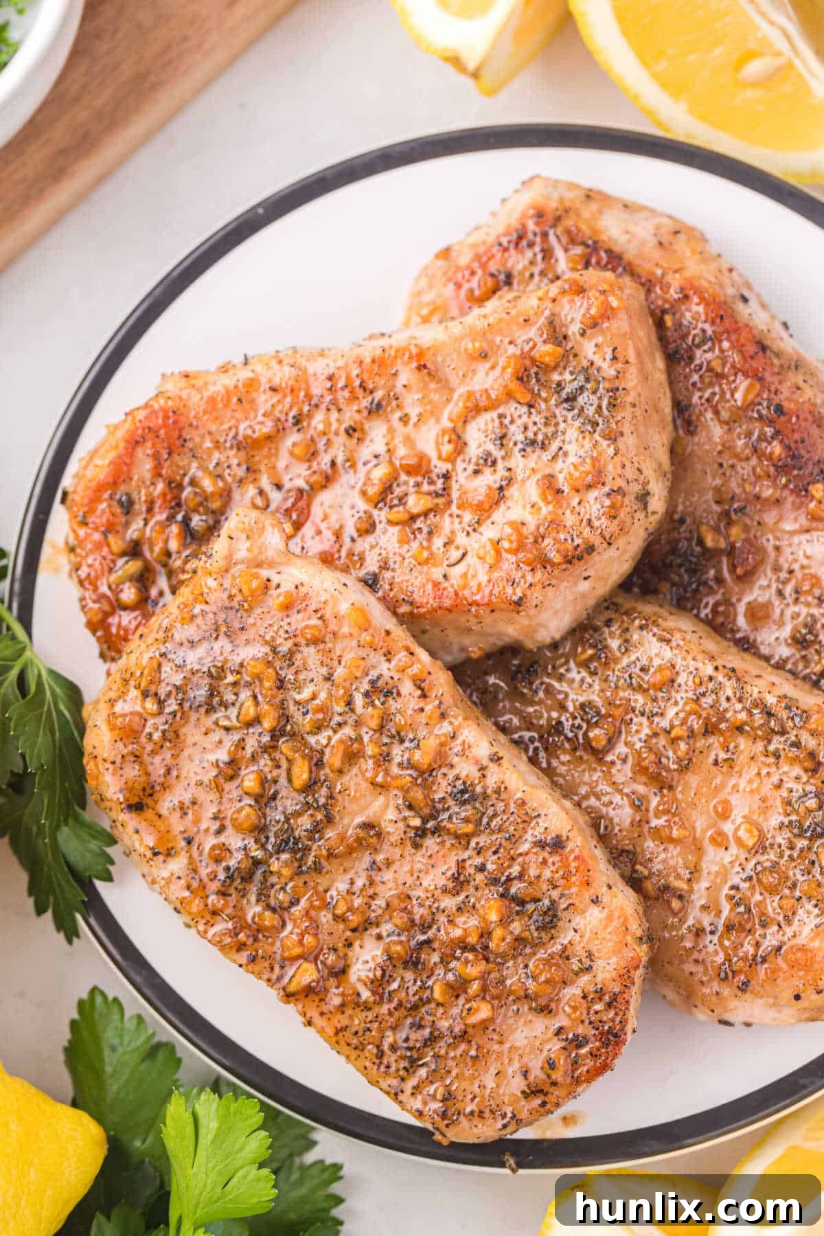 A pair of beautifully glazed honey garlic pork chops on a plate, garnished with fresh herbs, ready to be served.