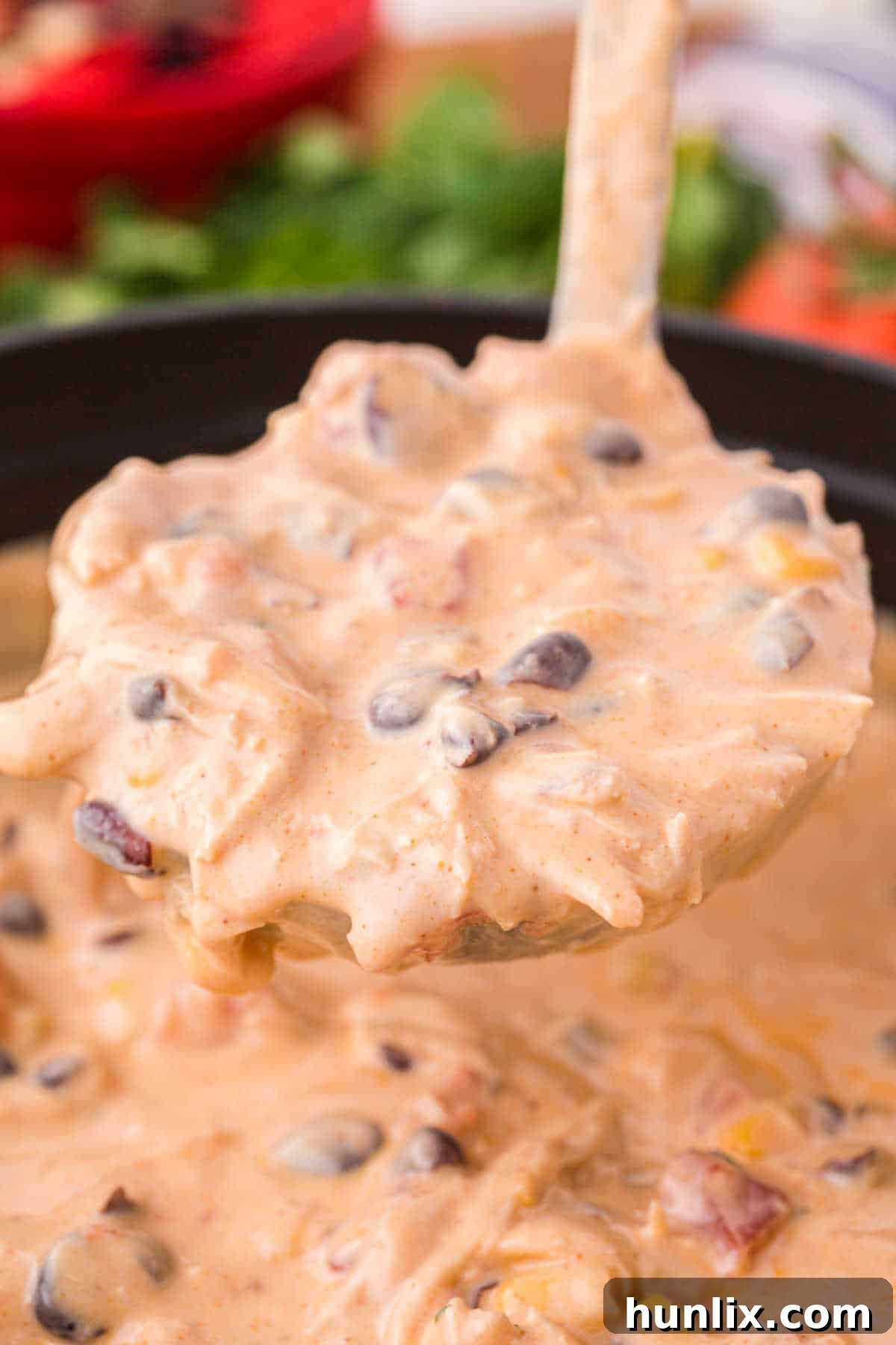 A ladle scooping rich and creamy Chicken Enchilada Soup from a pot, showcasing its inviting texture.