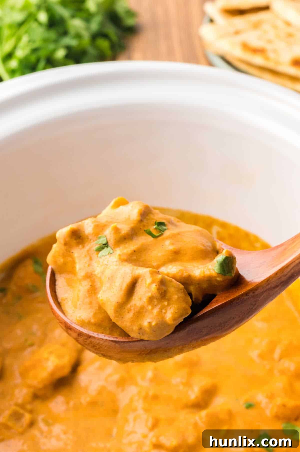 Butter chicken in a wooden ladle.