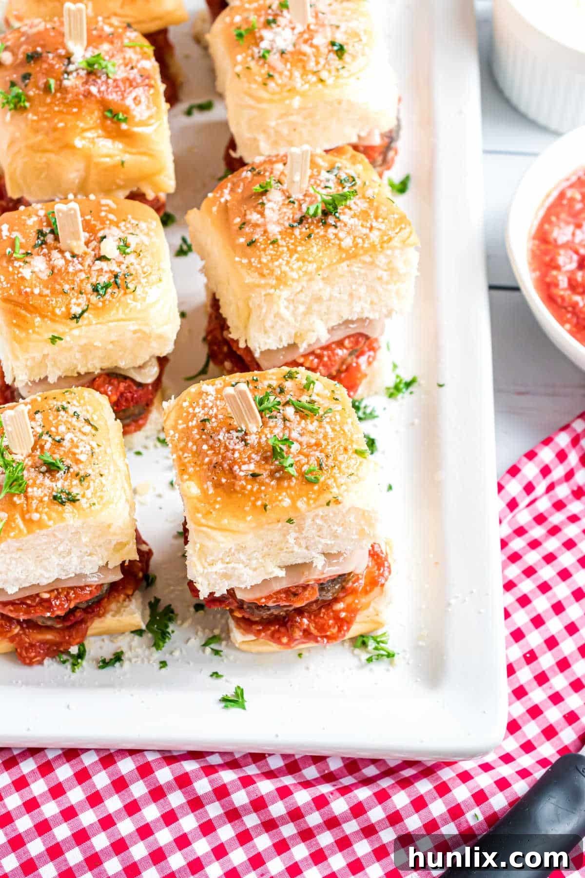 A platter of fully assembled meatball sliders, each with a toothpick.