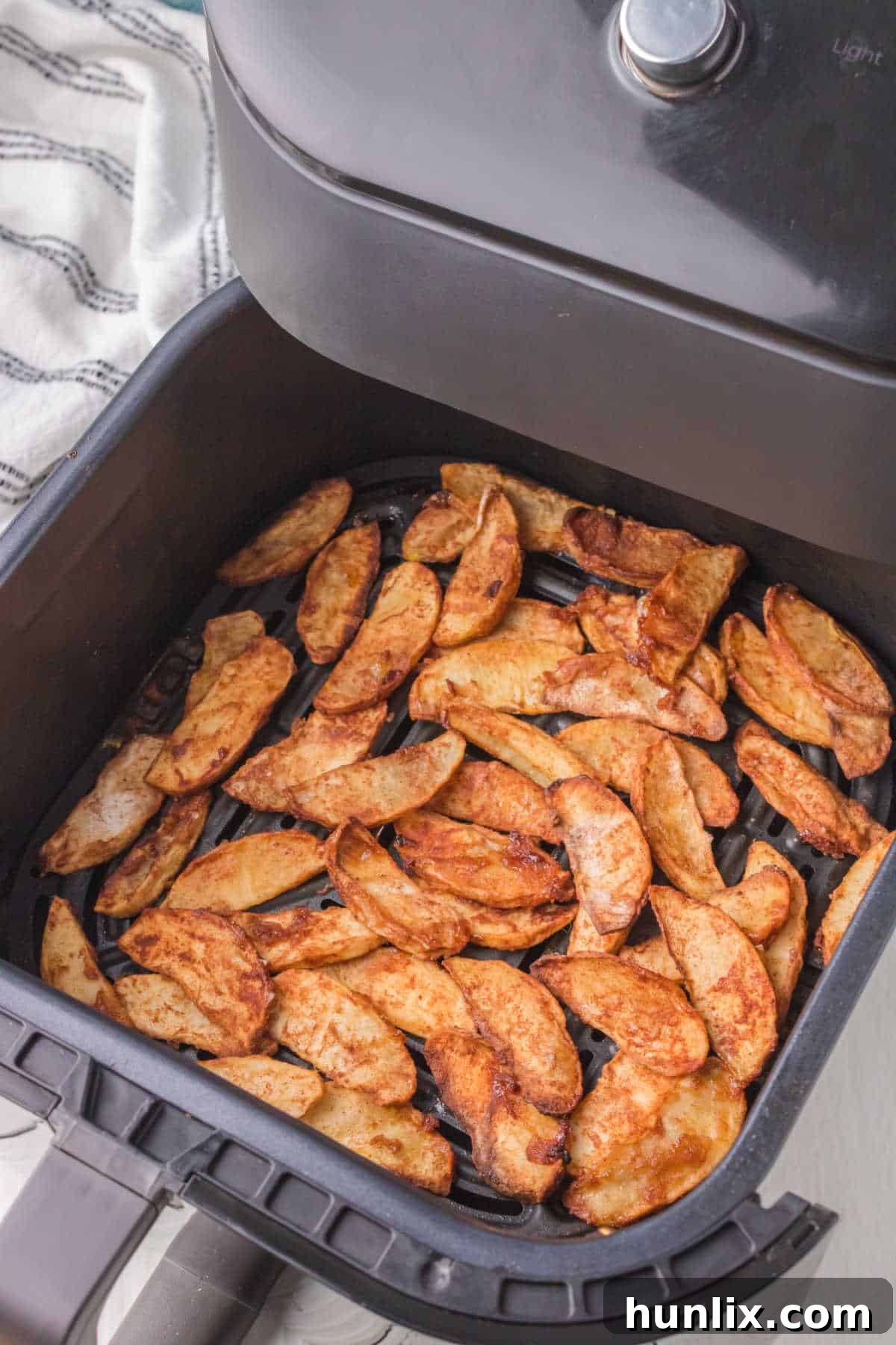 Apples cooked in an air fryer basket, golden brown and glistening.