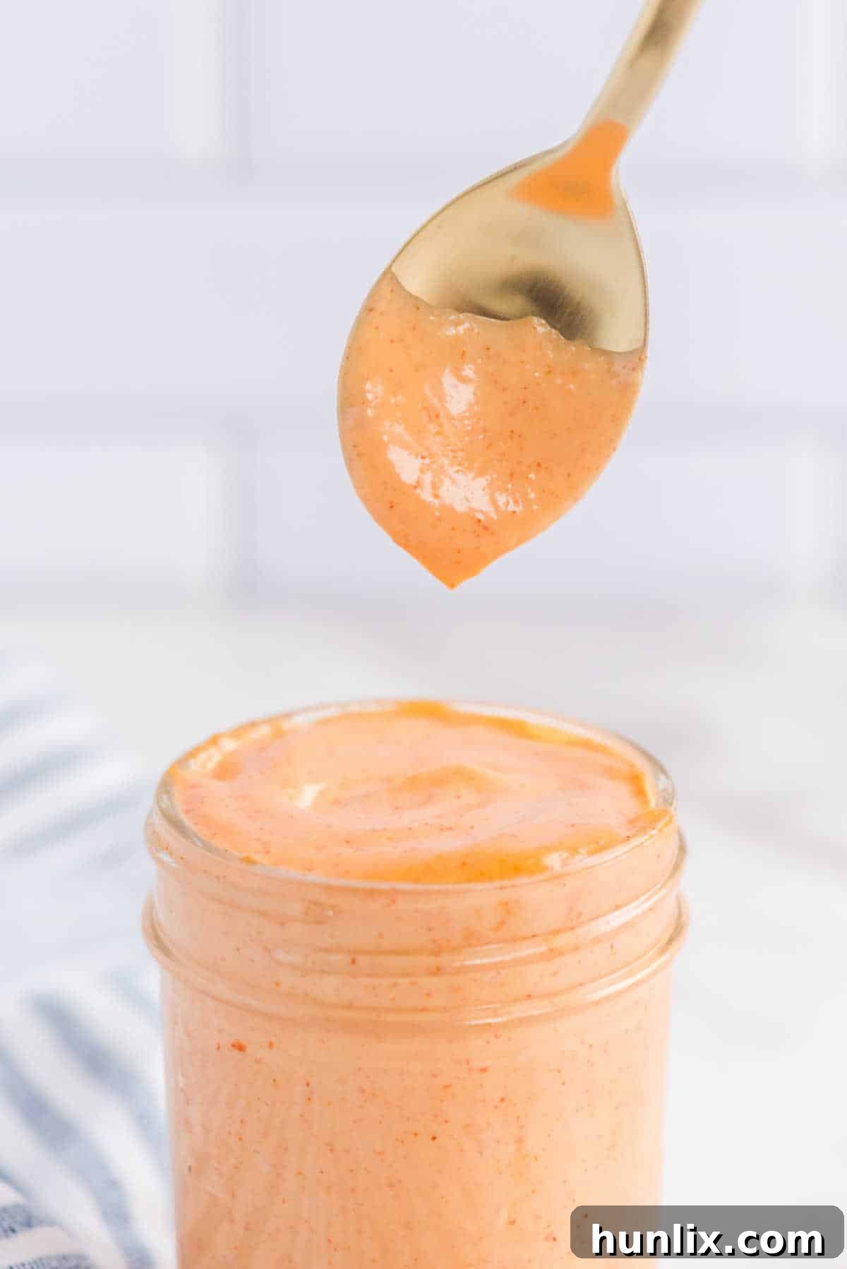 Yum Yum Sauce in a jar with a spoon resting on top, ready to use.