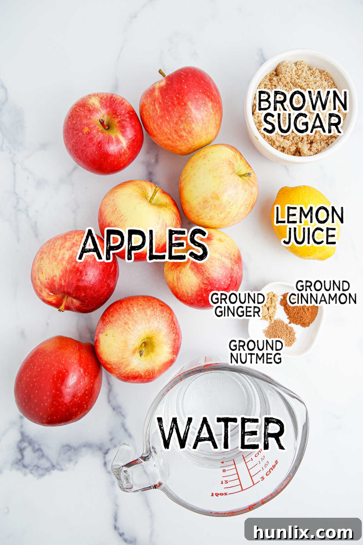 A collection of fresh apples, brown sugar, lemon, water, and spices laid out, ready to be transformed into apple compote.