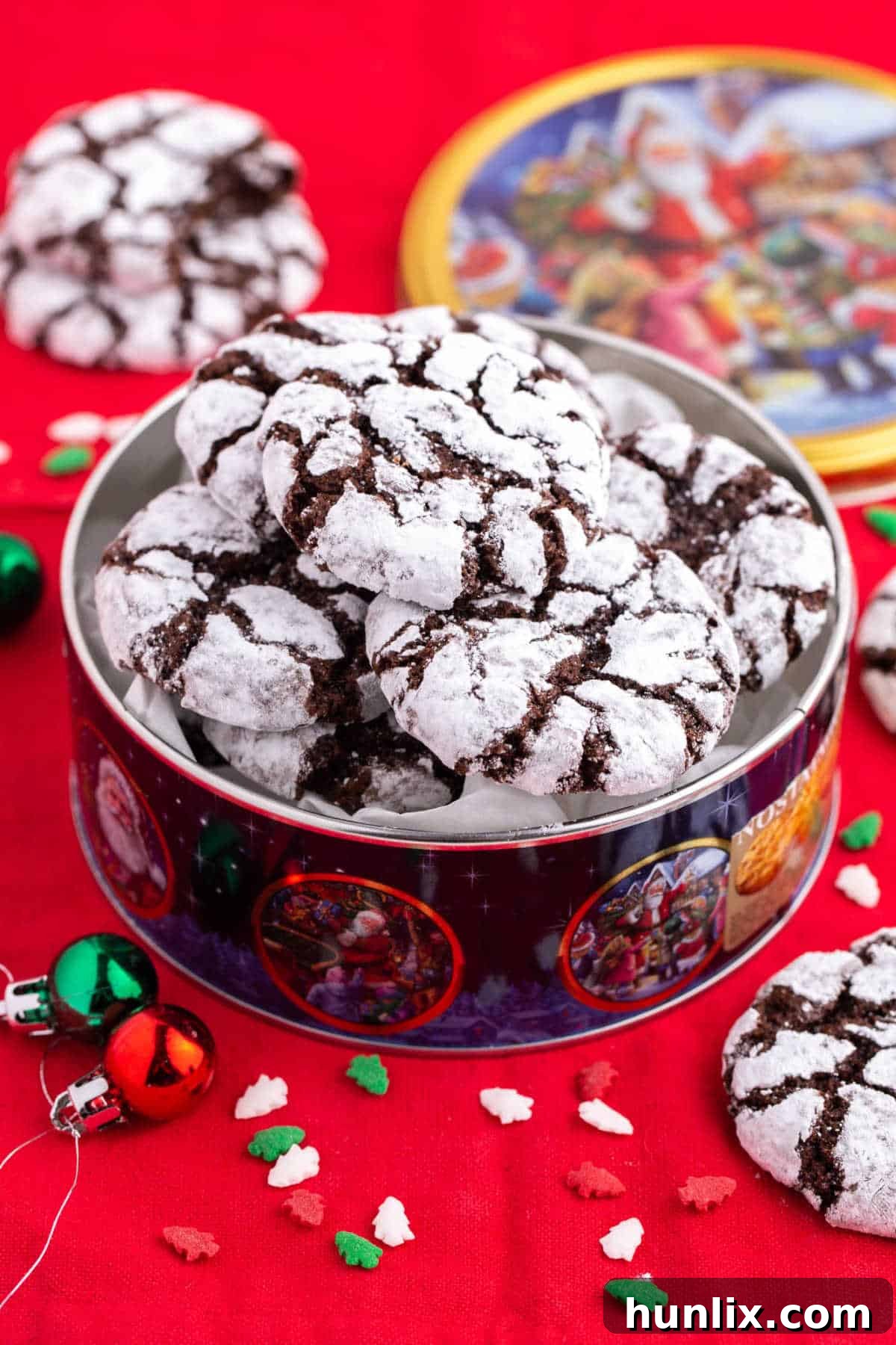 A festive tin filled with freshly baked Chocolate Crinkle Cookies, dusted with powdered sugar, ready for holiday gifting or sharing.