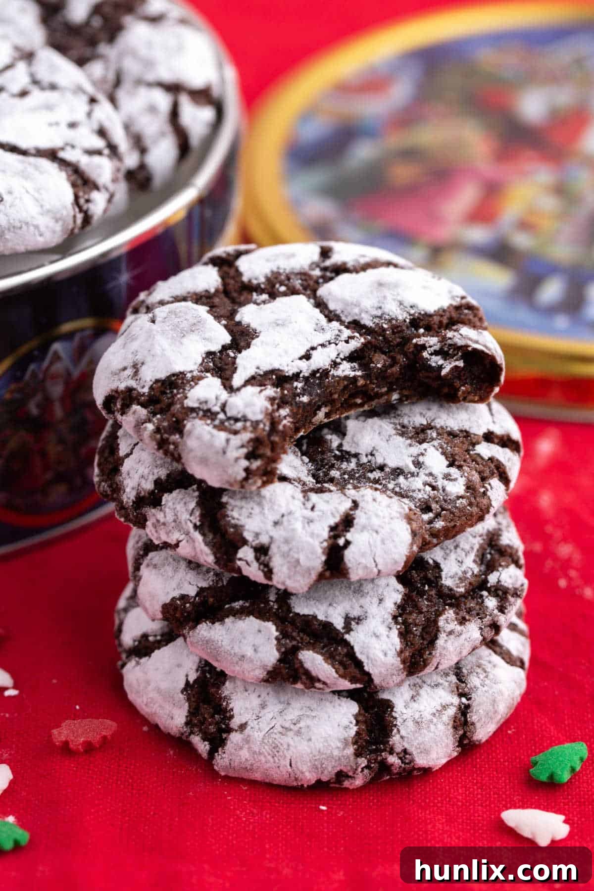 A charming stack of several chocolate crinkle cookies, each perfectly crinkled and dusted with powdered sugar, creating an inviting visual of holiday cheer and deliciousness.