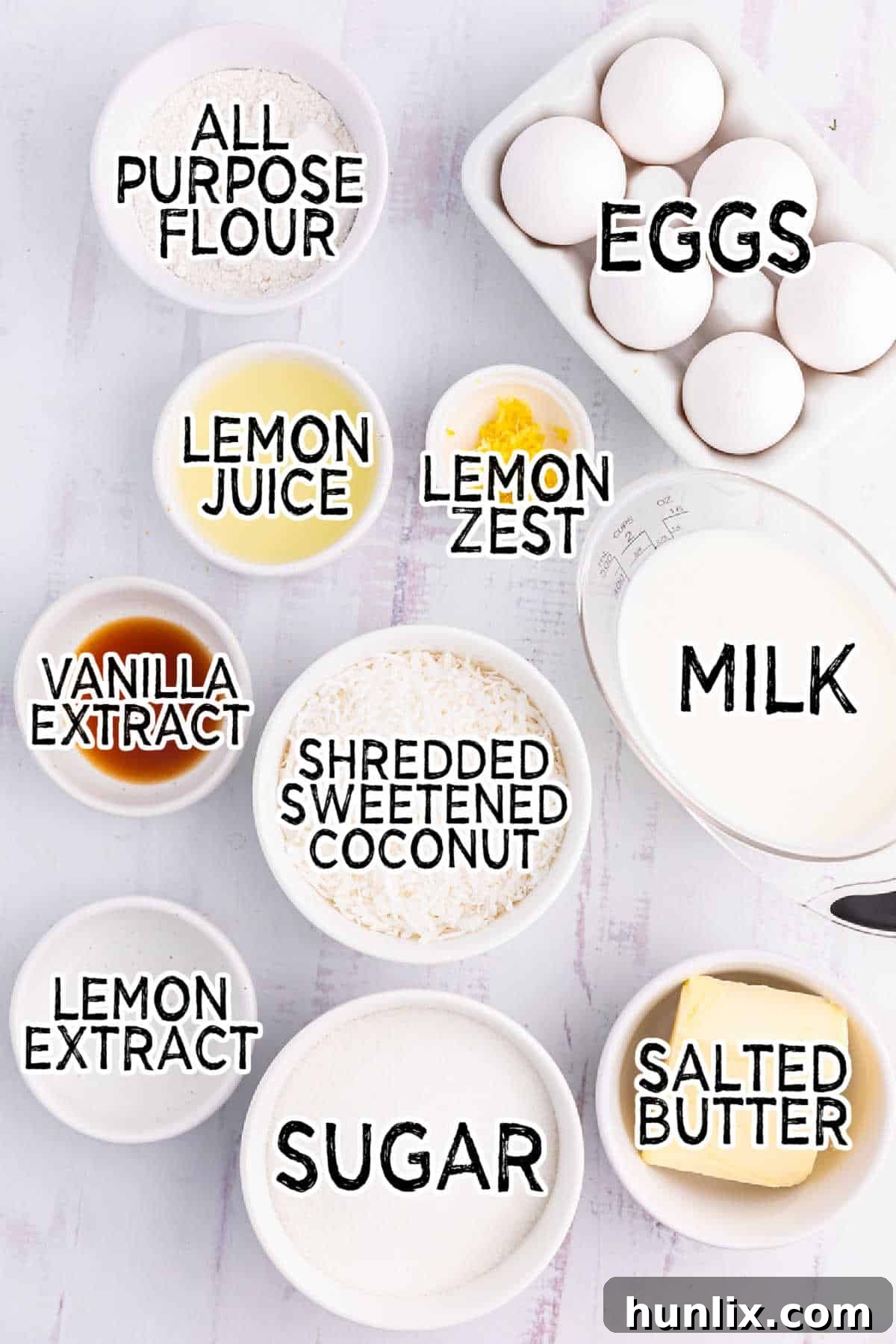 A selection of ingredients laid out on a table, including lemons, eggs, butter, sugar, flour, milk, and shredded coconut, ready for making Lemon Impossible Pie.