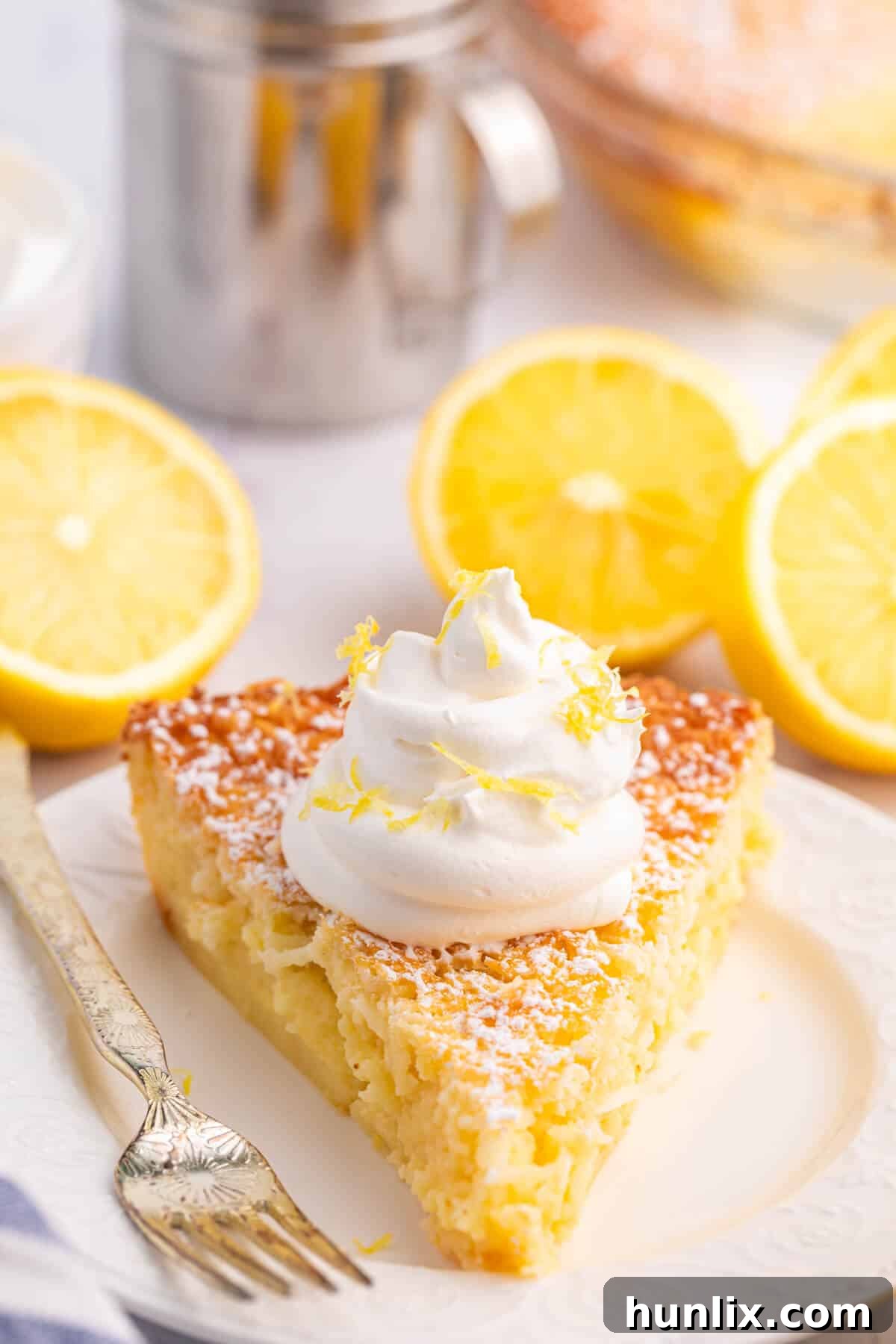 A slice of Lemon Impossible Pie on a white plate with a fork.