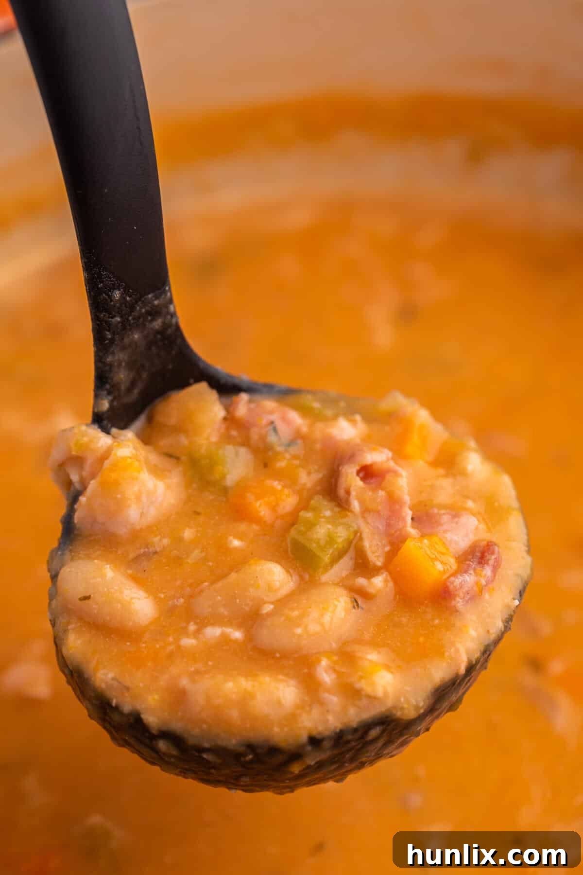 Bean with bacon soup in a ladle.