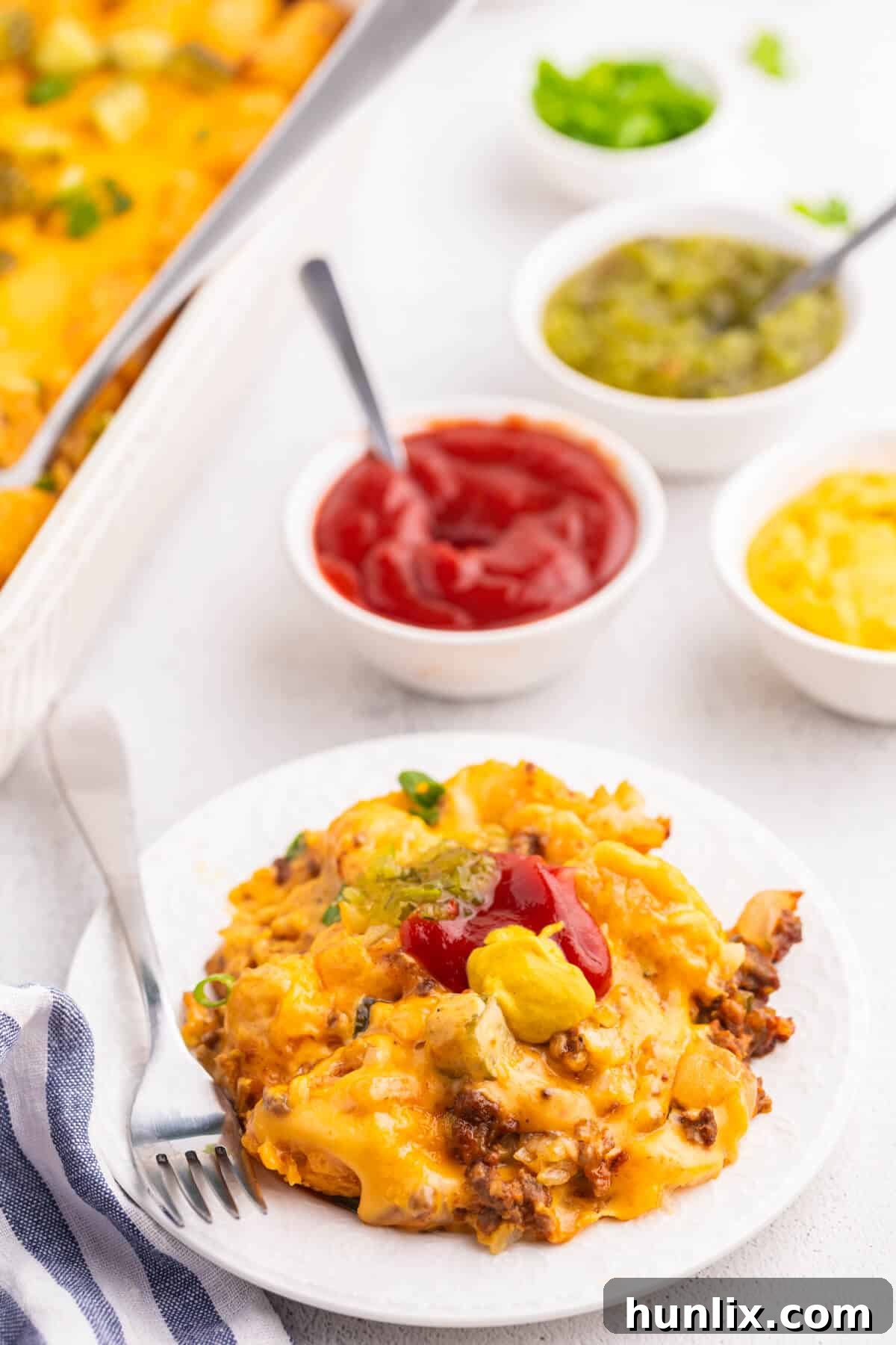 A scoop of cheeseburger tater tot casserole on a plate with a fork.