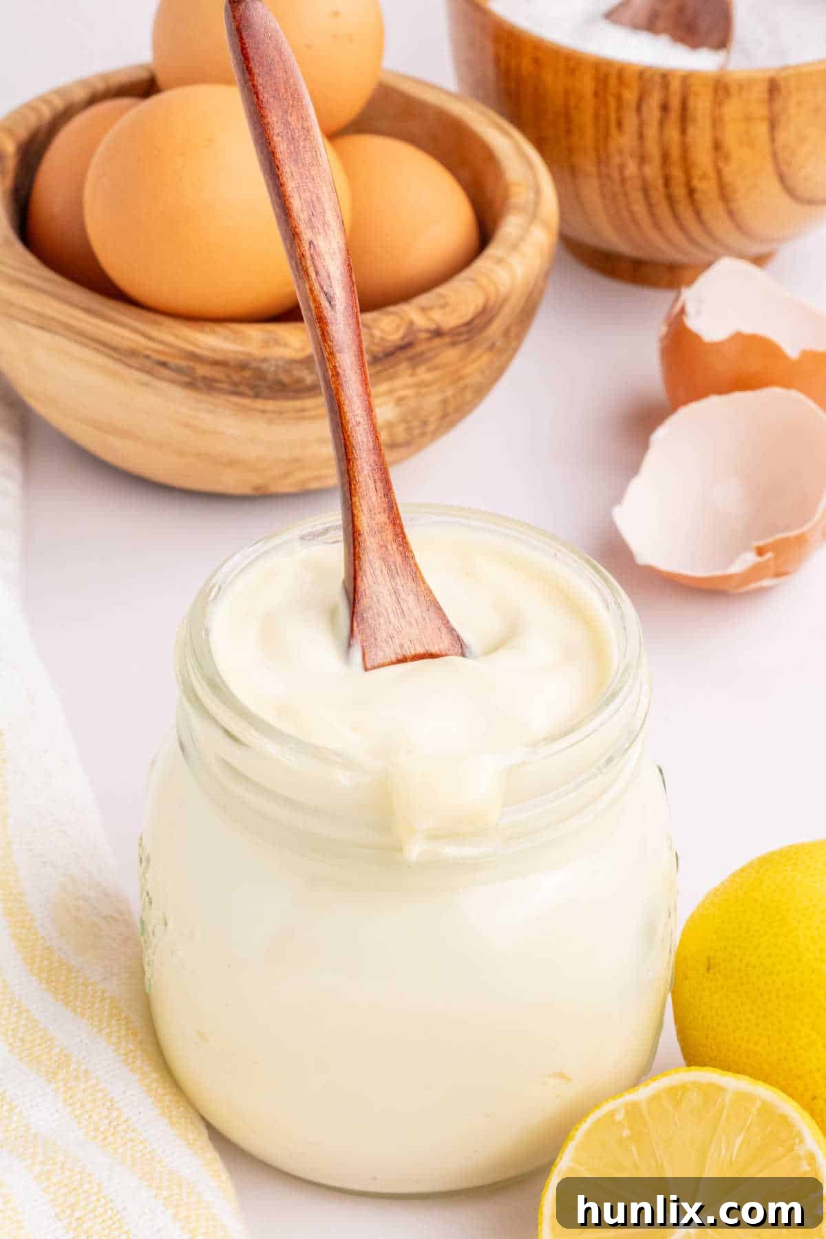 A jar of mayonnaise with a wooden spoon in it, showcasing its creamy texture.