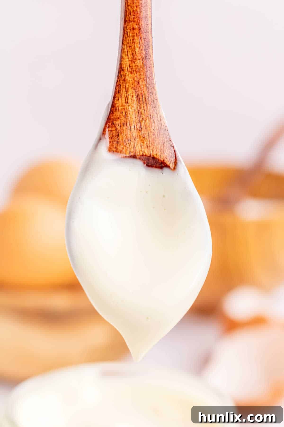 A wooden spoon covered in creamy homemade mayonnaise, highlighting its smooth texture.