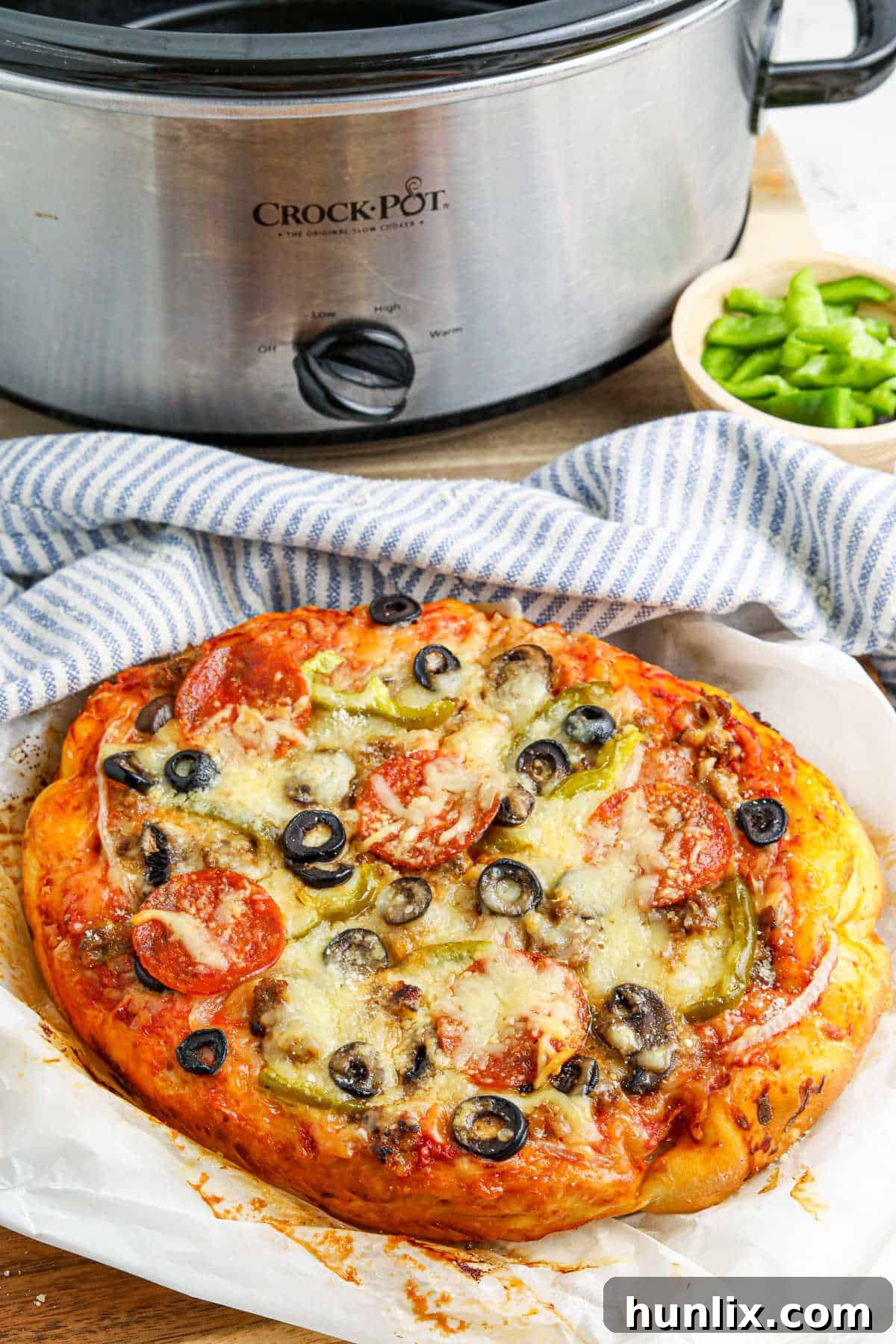 Freshly cooked Crockpot supreme pizza resting on parchment paper after being removed from the slow cooker.