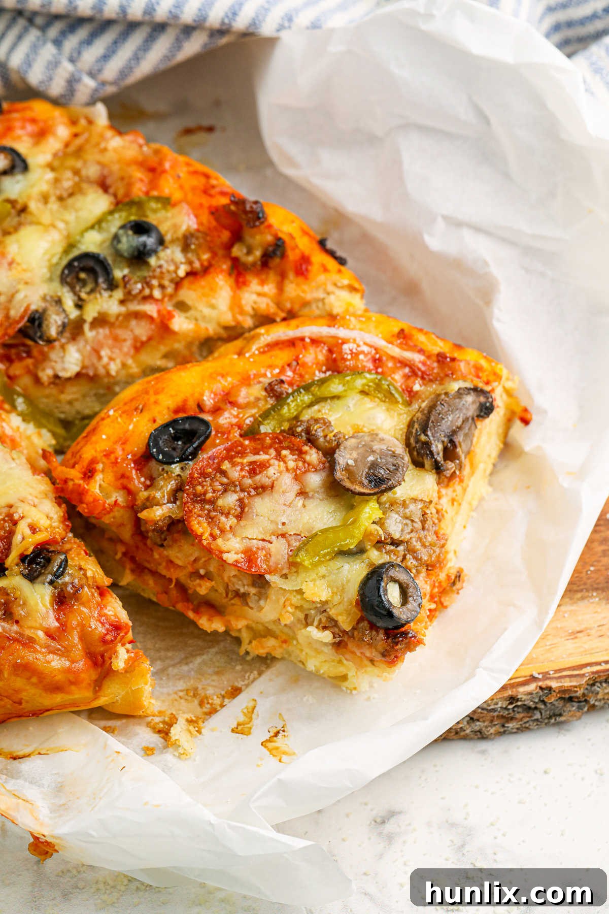Slices of Crockpot supreme pizza on parchment paper, showcasing the fluffy crust and generous toppings.