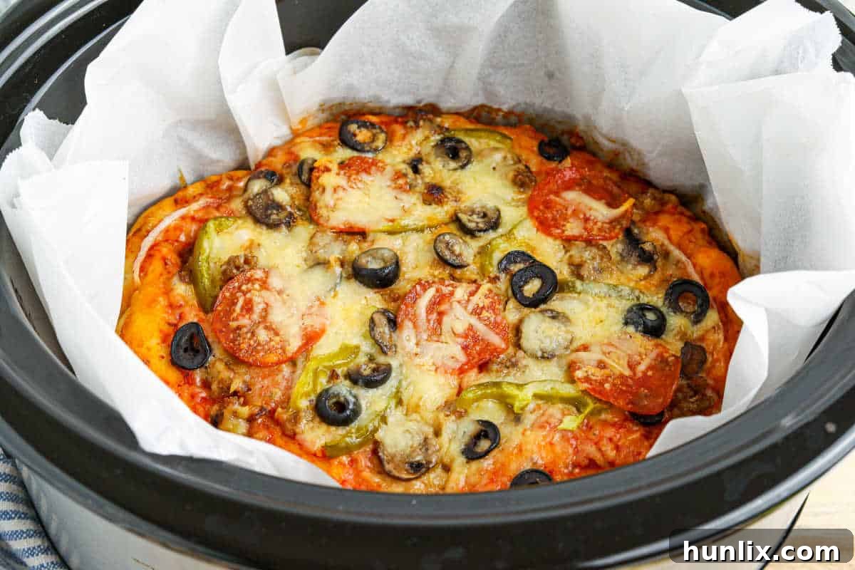 A whole Crockpot supreme pizza, cooked and bubbly, still in the slow cooker before serving.