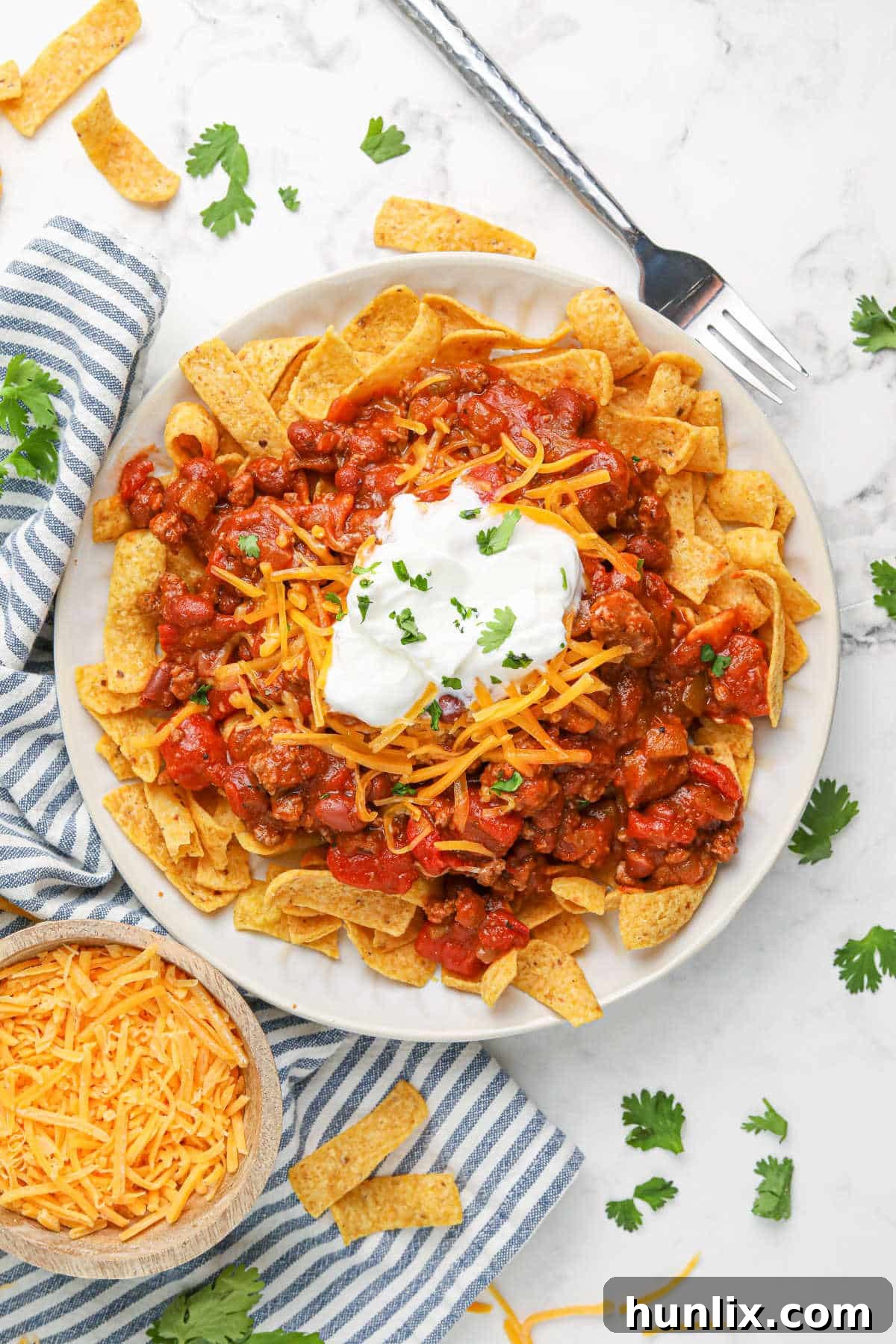 A serving of Frito Chili Pie garnished with fresh cilantro and sour cream.