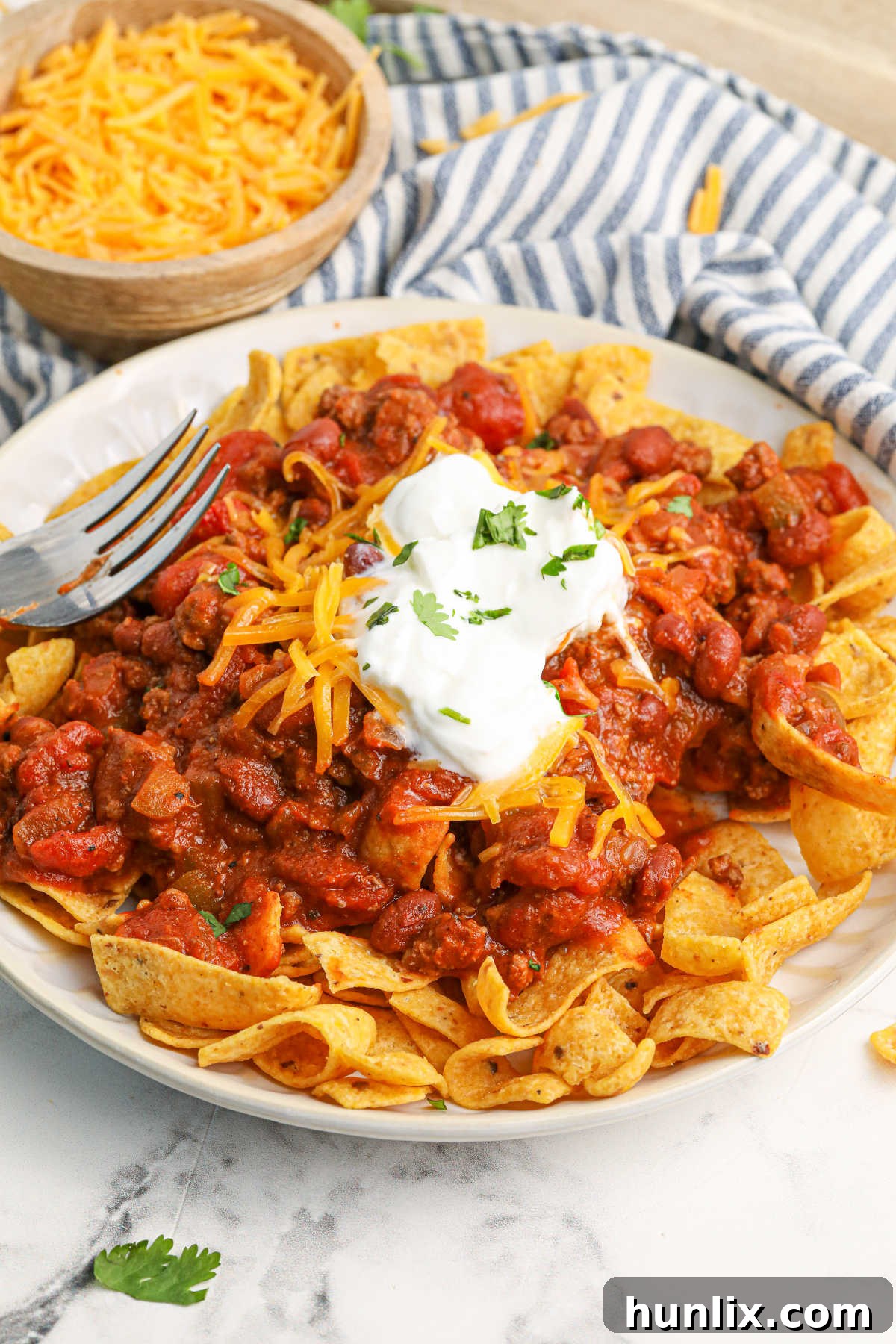 Frito Chili Pie served on a plate with a fork, ready to eat.