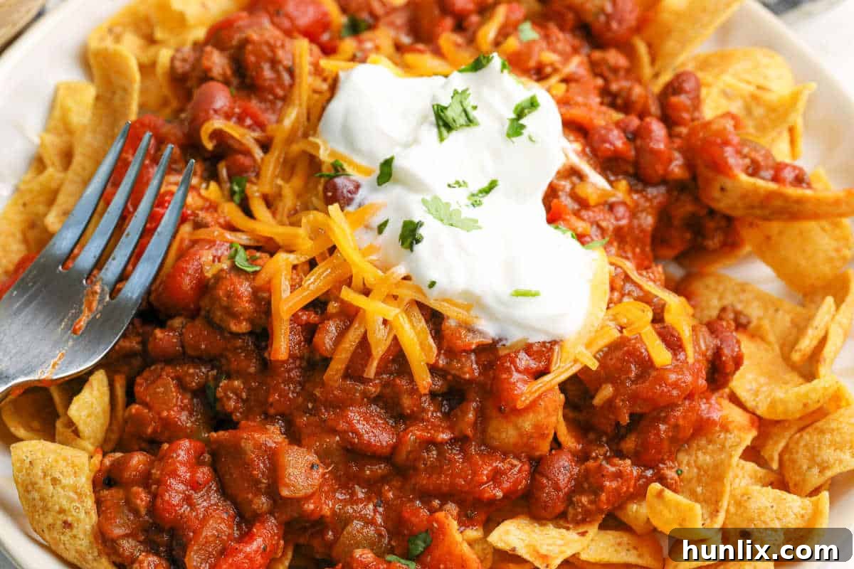 Another perspective of Frito Chili Pie on a plate with a fork.