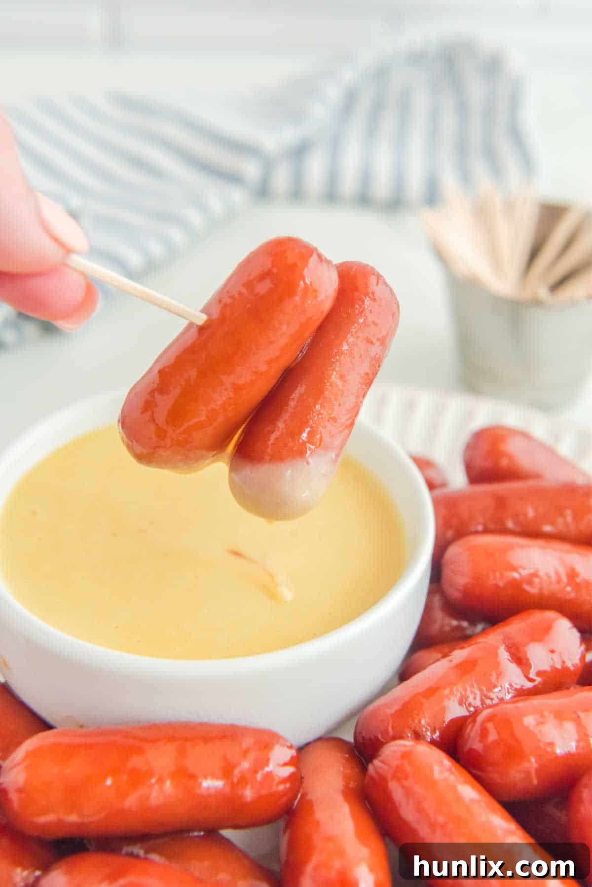 Little smokies being dipped into honey mustard sauce.