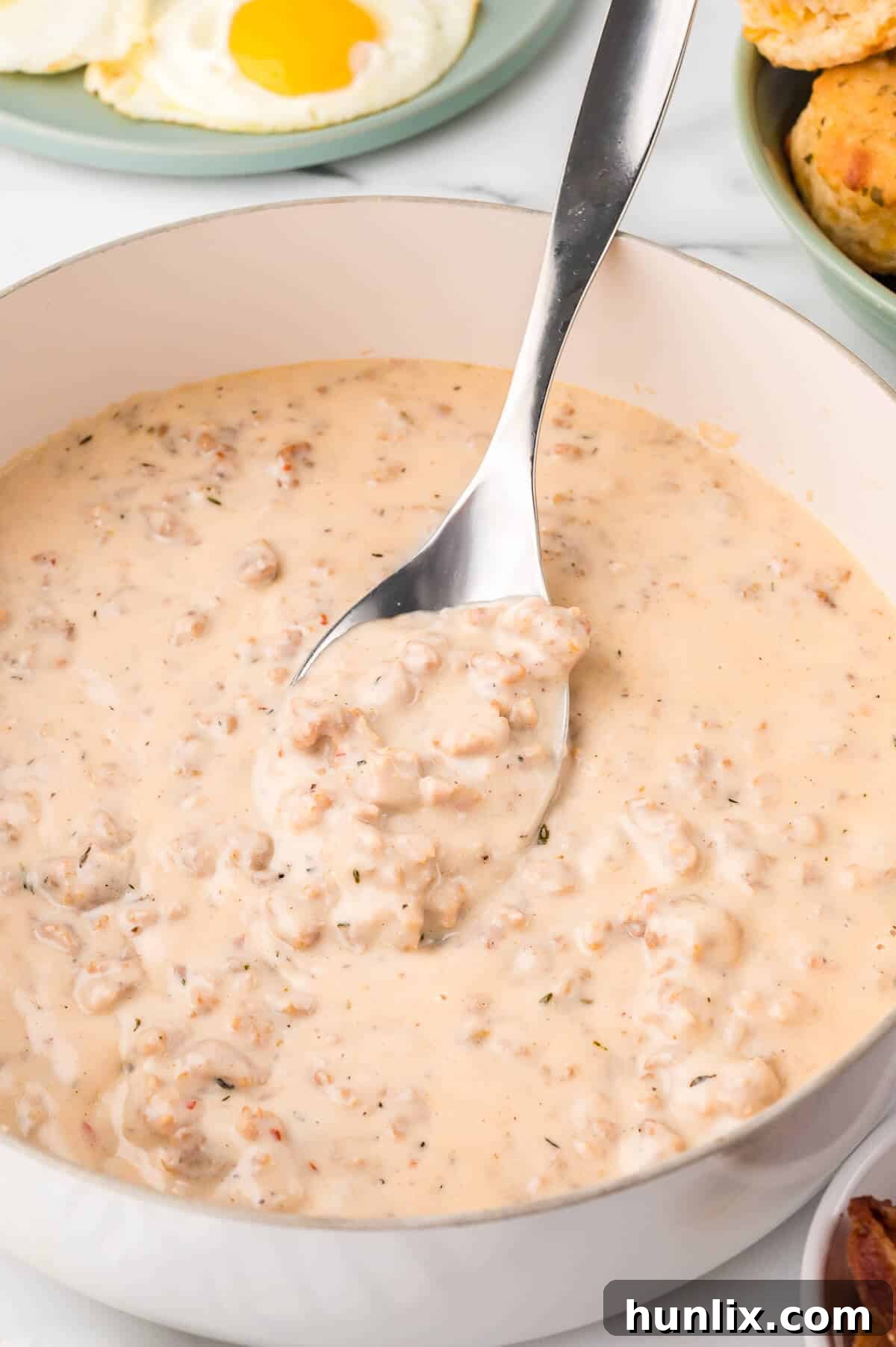 Sausage gravy in a pot with a serving spoon.