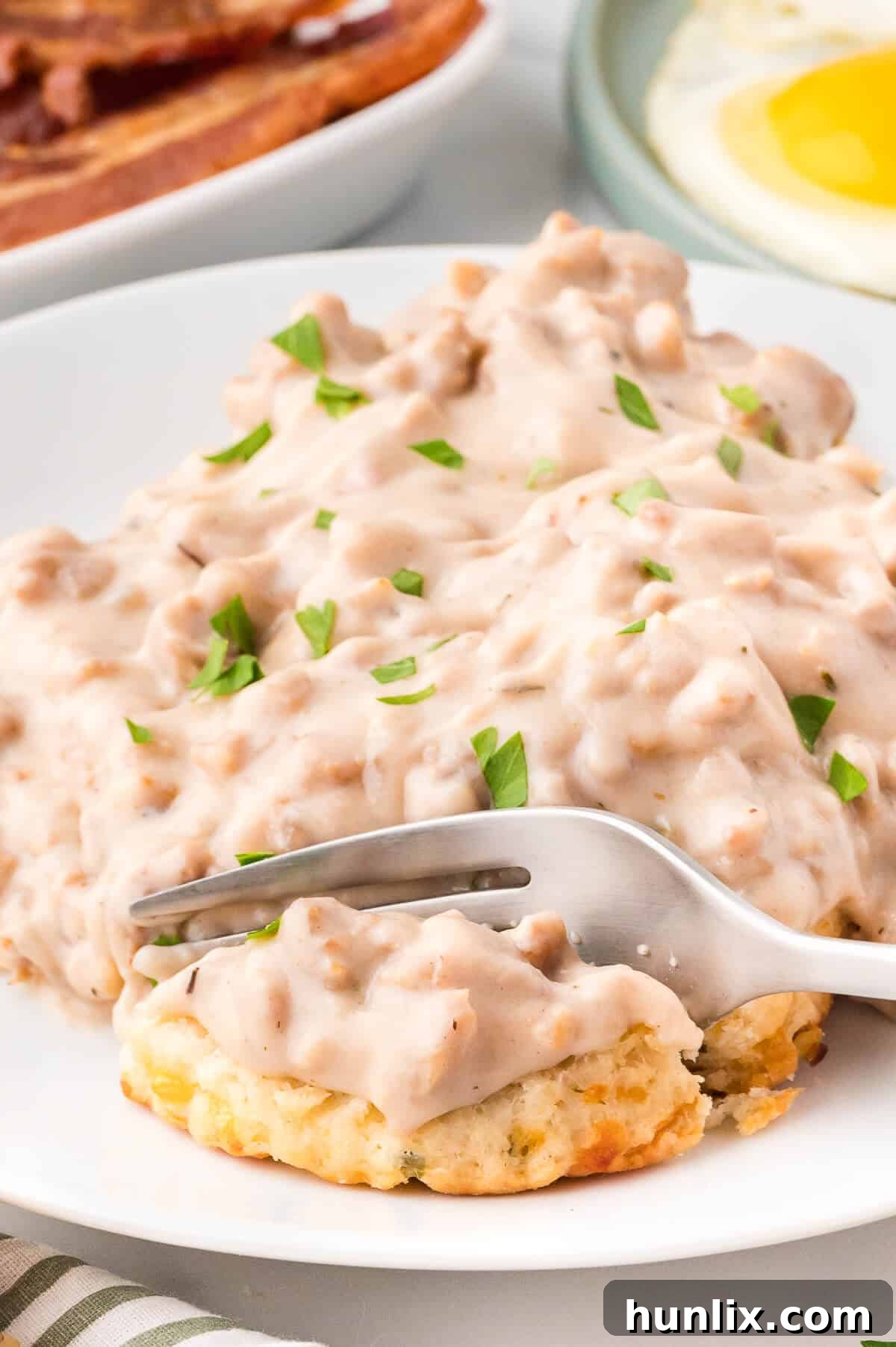 Sausage gravy and biscuits on a plate with a fork.